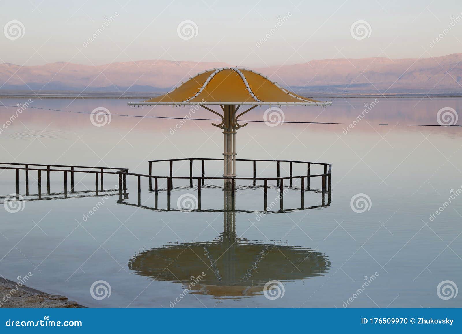 gazebo for sun protection reflected in dead sea water at sunset