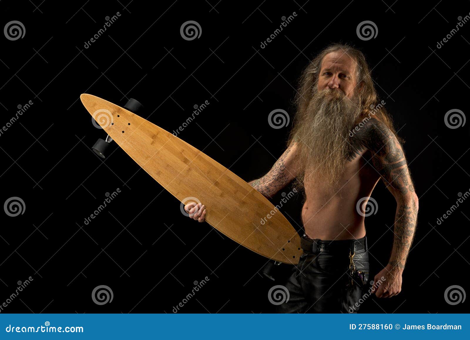 Gebaarde oudere mens met een lange raad. Een oudere mens met een lange haar en een baard, op een zwarte achtergrond die een lang skateboard houden.