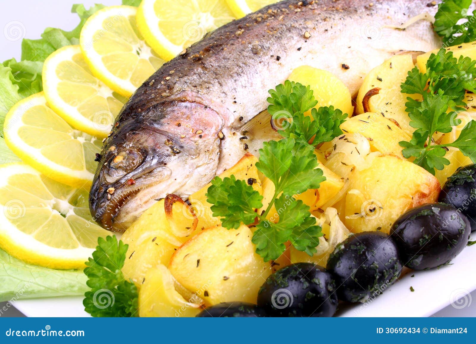 Gebackene Forelle Mit Kartoffeln, Oliven, Zitrone Und Salat Stockfoto ...