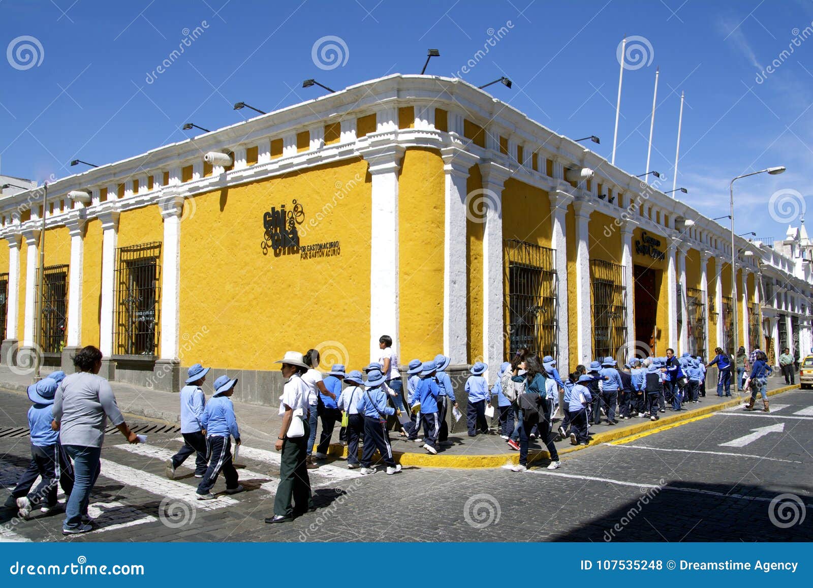 Gele straathoek en studenten in eenvormig, Arequipa, Peru. Jonge Peruviaanse schooljonge geitjes met zonhoeden tegen uv-Stralen die straat in historisch centrum kruisen Arequipa, Peru