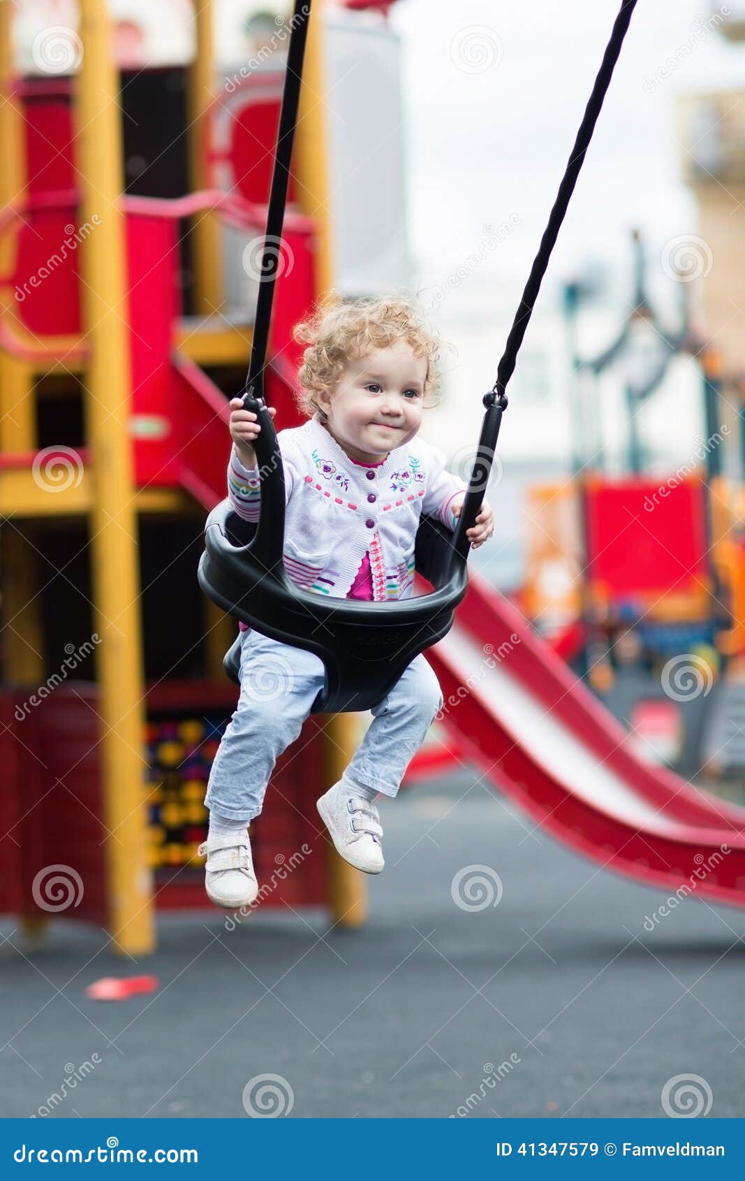 Gelukkig babymeisje die van een schommelingsrit op een speelplaats genieten