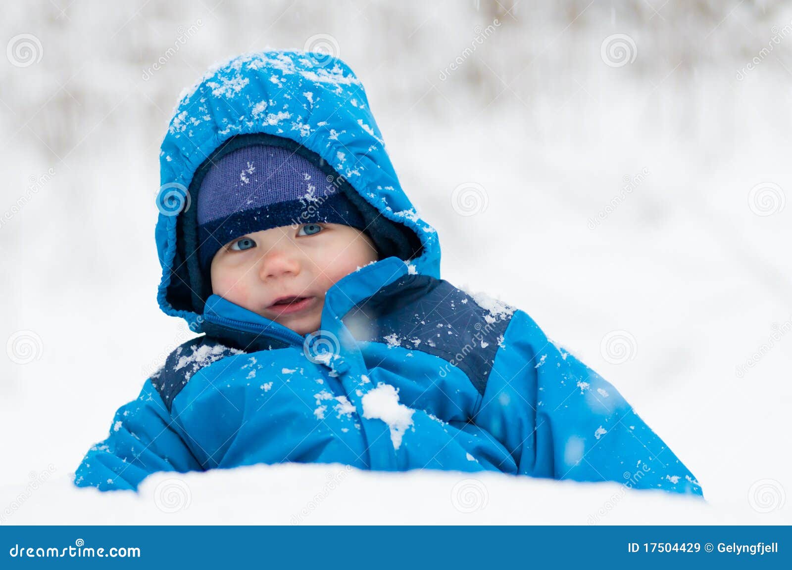 Gelukkig in de sneeuw. Het gelukkige babyjongen spelen in de sneeuw