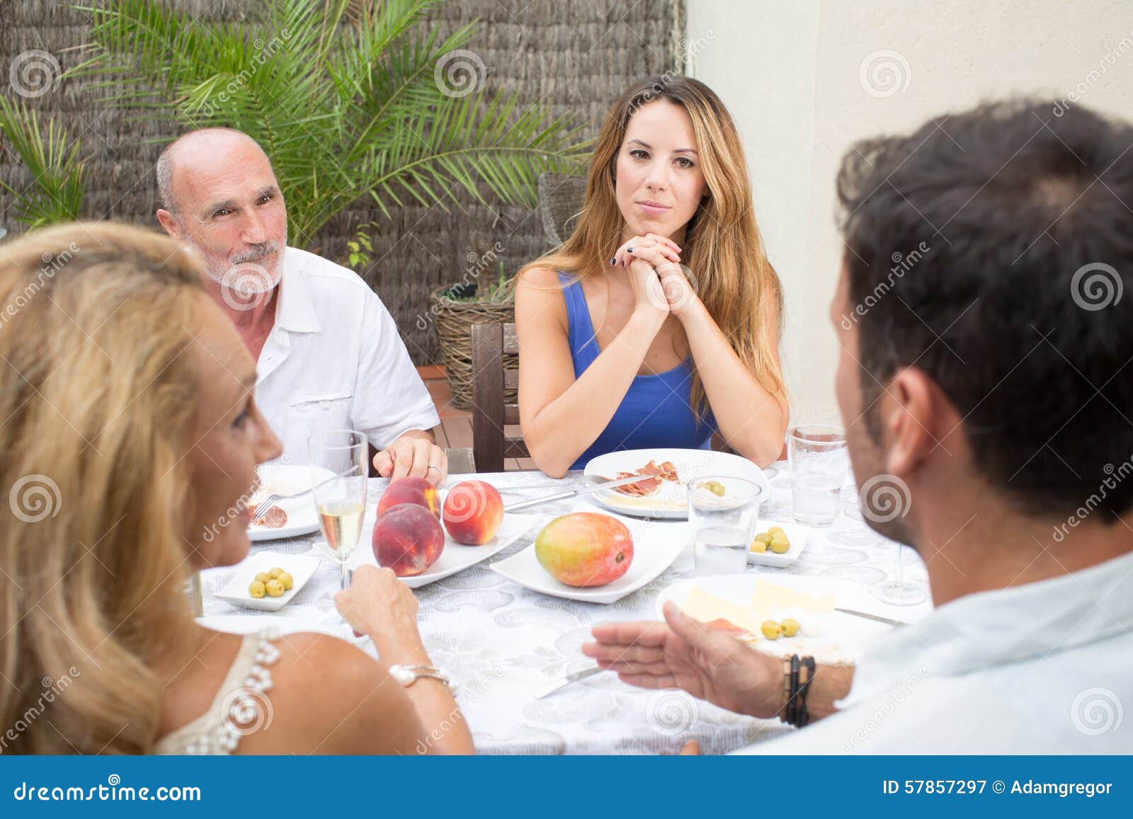 Gelukkige familie die in tuin spreken. Gelukkige familie die terwijl het hebben van voedsel op terras spreken