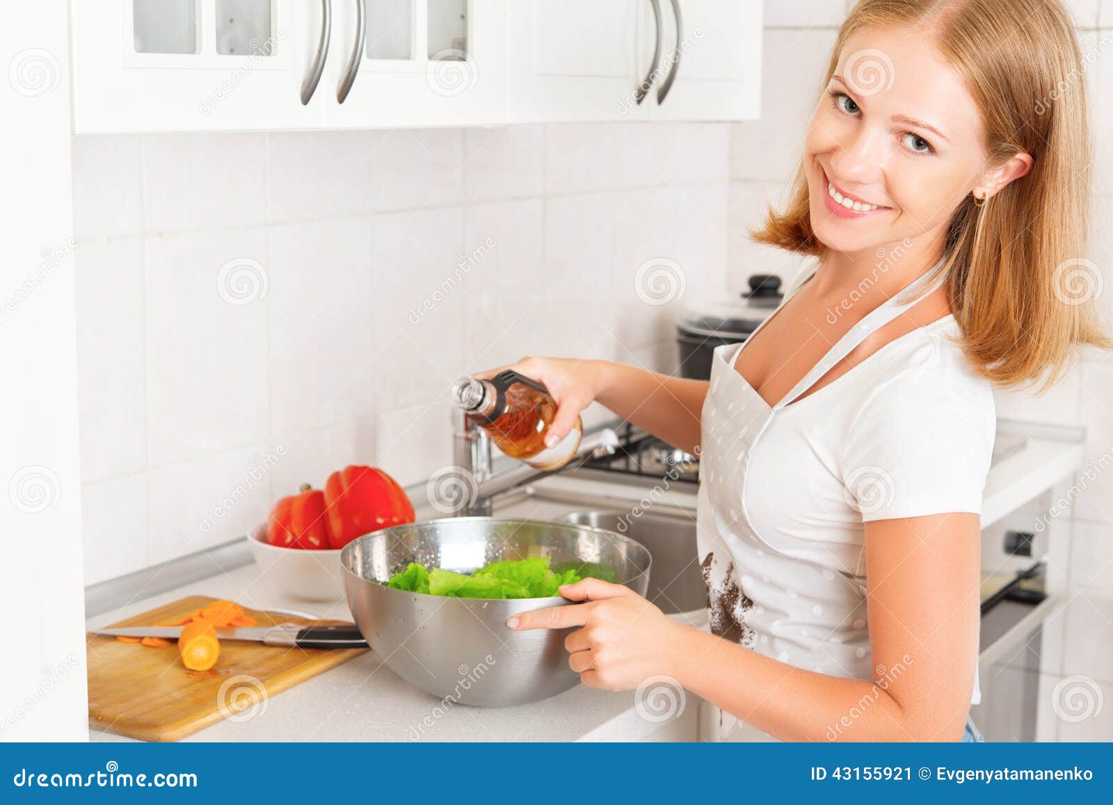 Gelukkige vrouwenhuisvrouw die salade in keuken voorbereiden. Gelukkige vrouwenhuisvrouw die plantaardige salade in de keuken voorbereiden