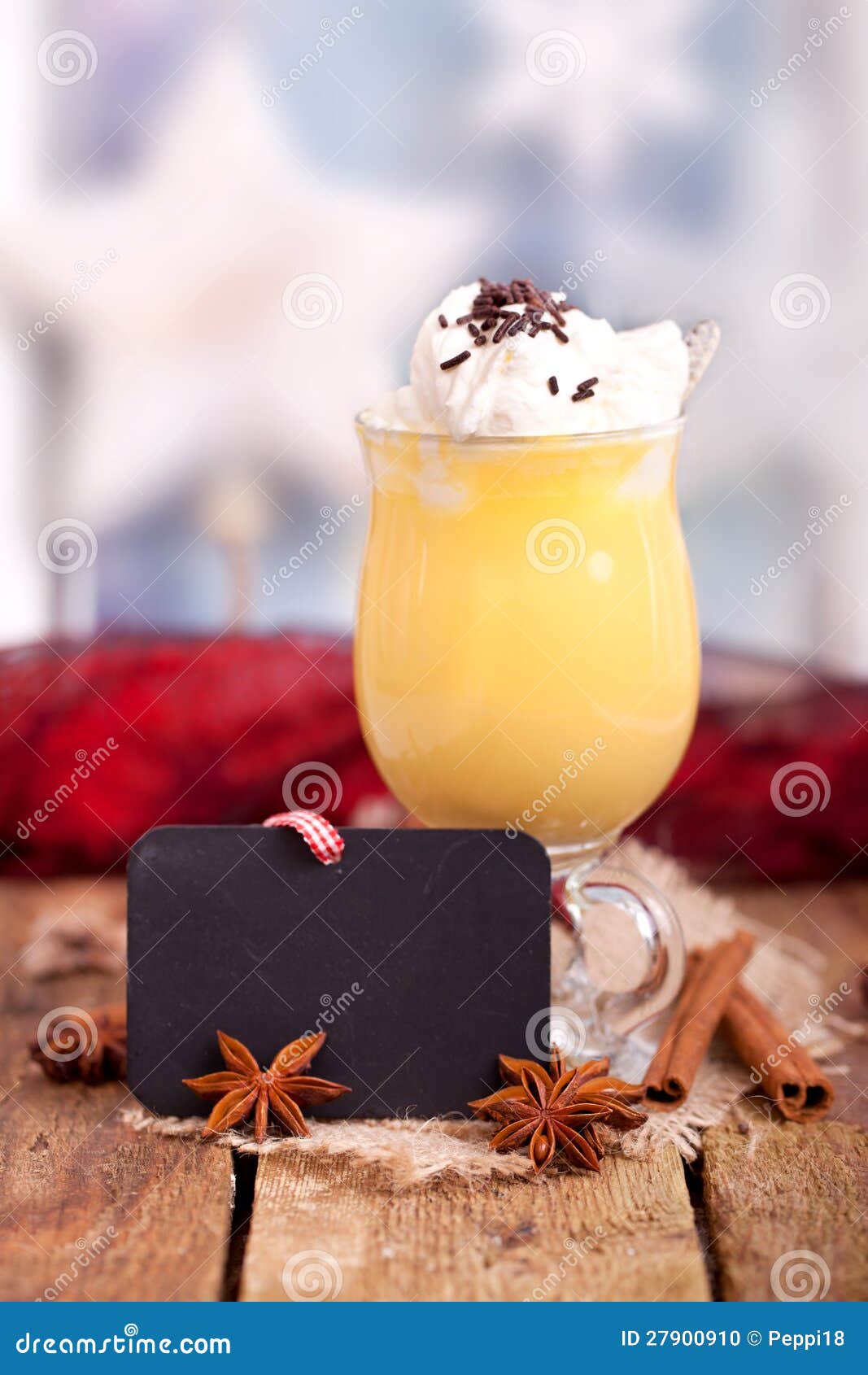 A gemada amarela fresca com a semente da canela e do anis para o Natal na placa de madeira rústica, com Natal borrado stars no fundo