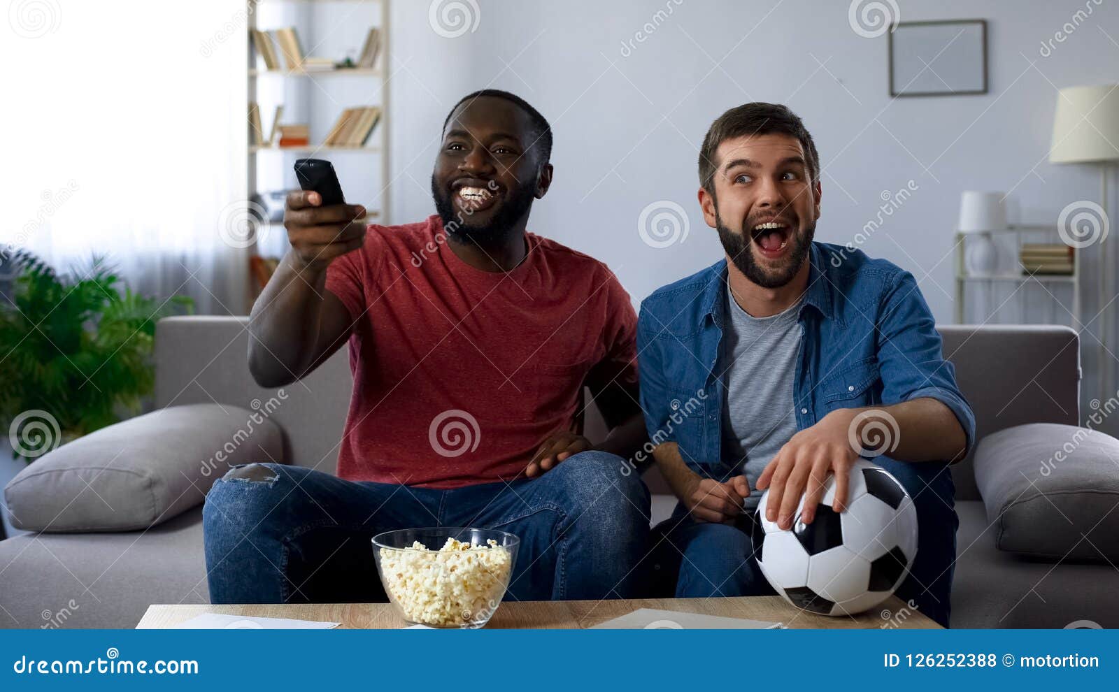 Gemischtrassige Kerle, die Fernsehen laut, Schluss des Fußballwettbewerbs mit Nationalmannschaft, Foto auf Lager machen