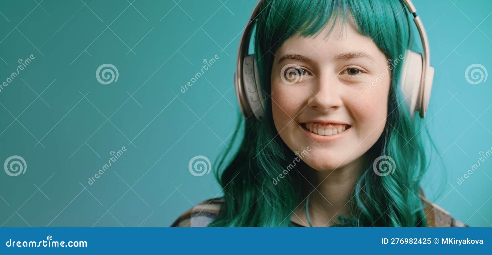 gen z teenager with green hair listens music in headphones. music subscription service concept.