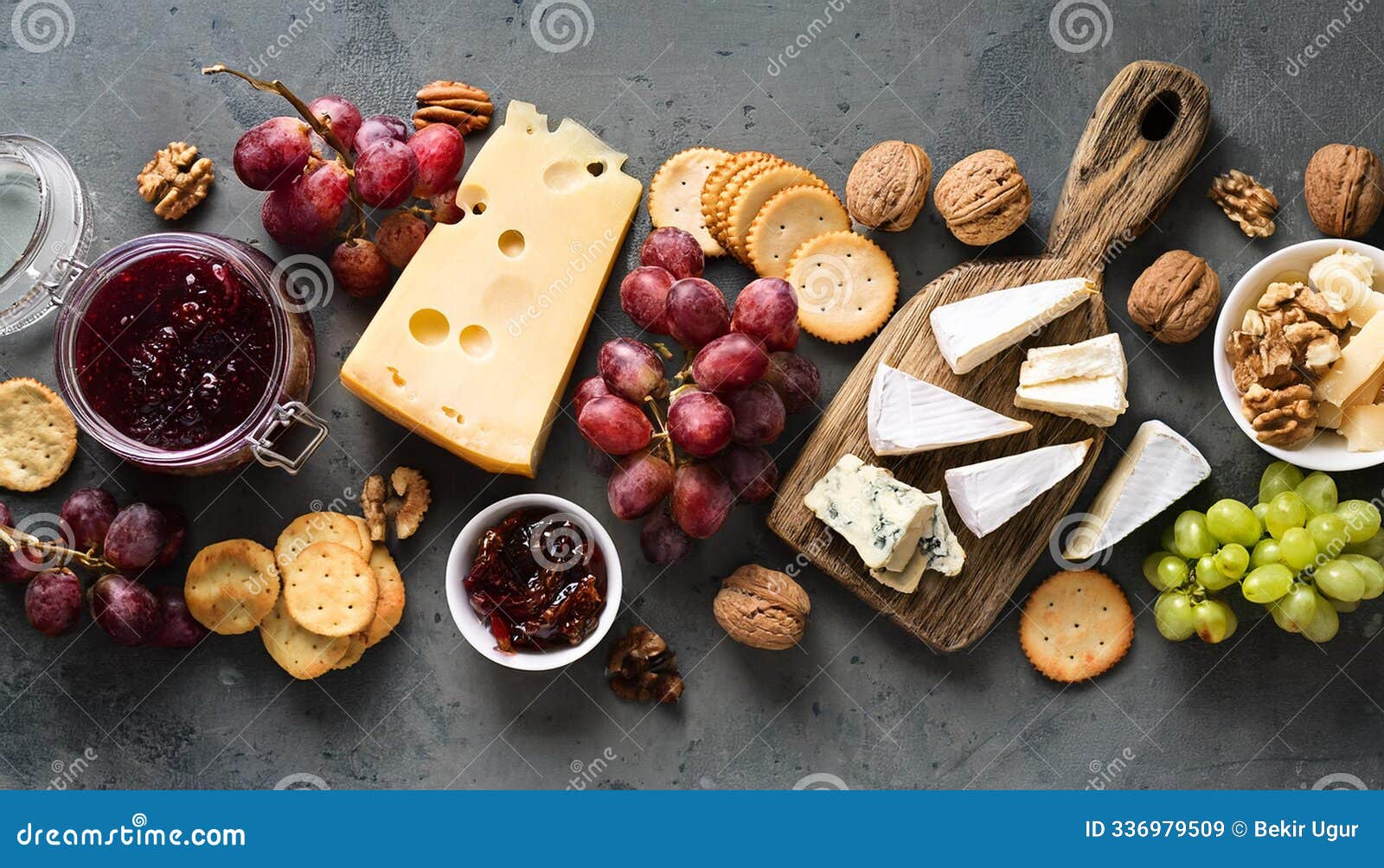 variety of wine snacks, jam and cheeses over grey background.