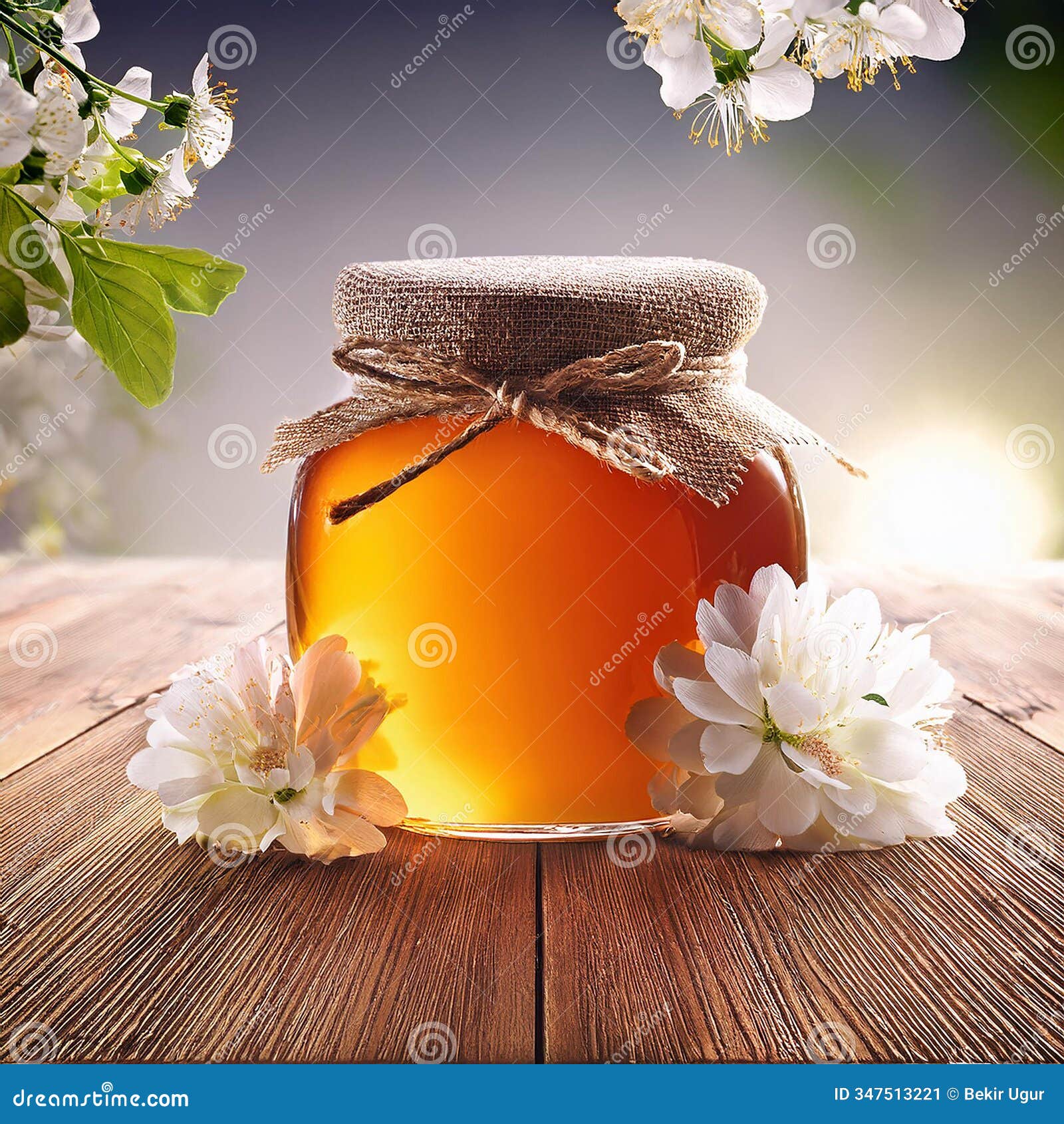 honey in a glass jar with white flowers on floor board