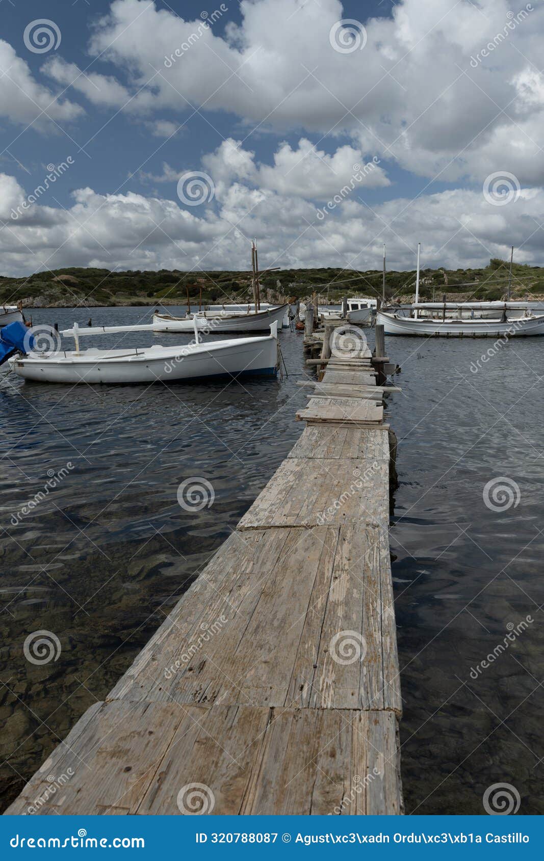 boats docked by wooden pier at port of sanitja, menorca