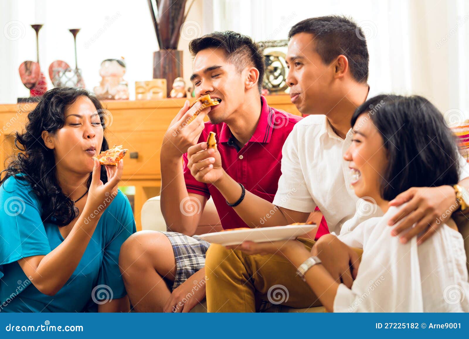 Gente asiática que come la pizza en el partido o cena y sonrisa