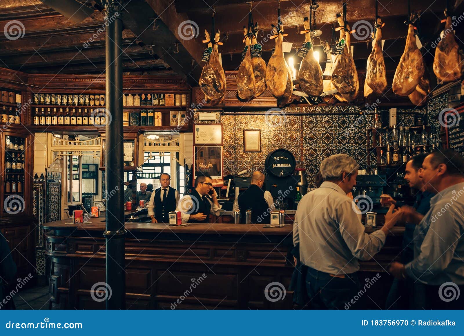 Gente Hablando Y Bebiendo Vino En El Bar O Restaurante Tradicional Con  Barra De Bar Y Piernas De Jamón Secas Imagen editorial - Imagen de licor,  bebida: 183756970
