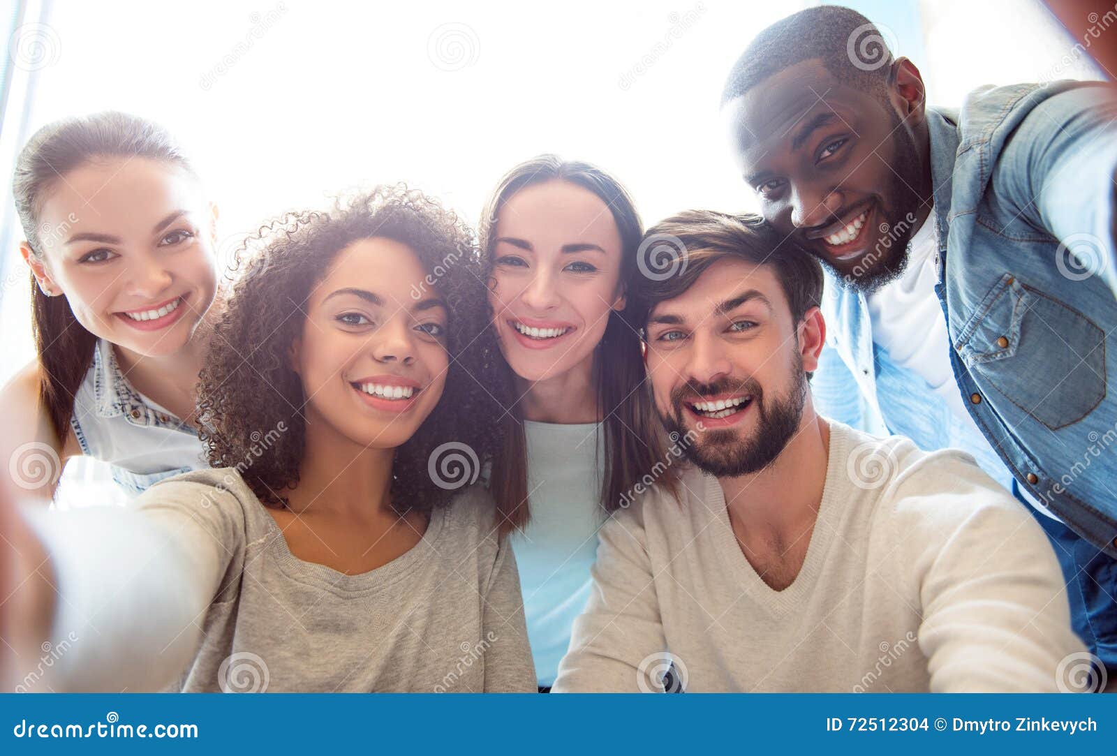 Amigos por siempre Gente joven moderna positiva y feliz que se sienta junto y que toma una fotografía del selfie mientras que estando en un humor amistoso