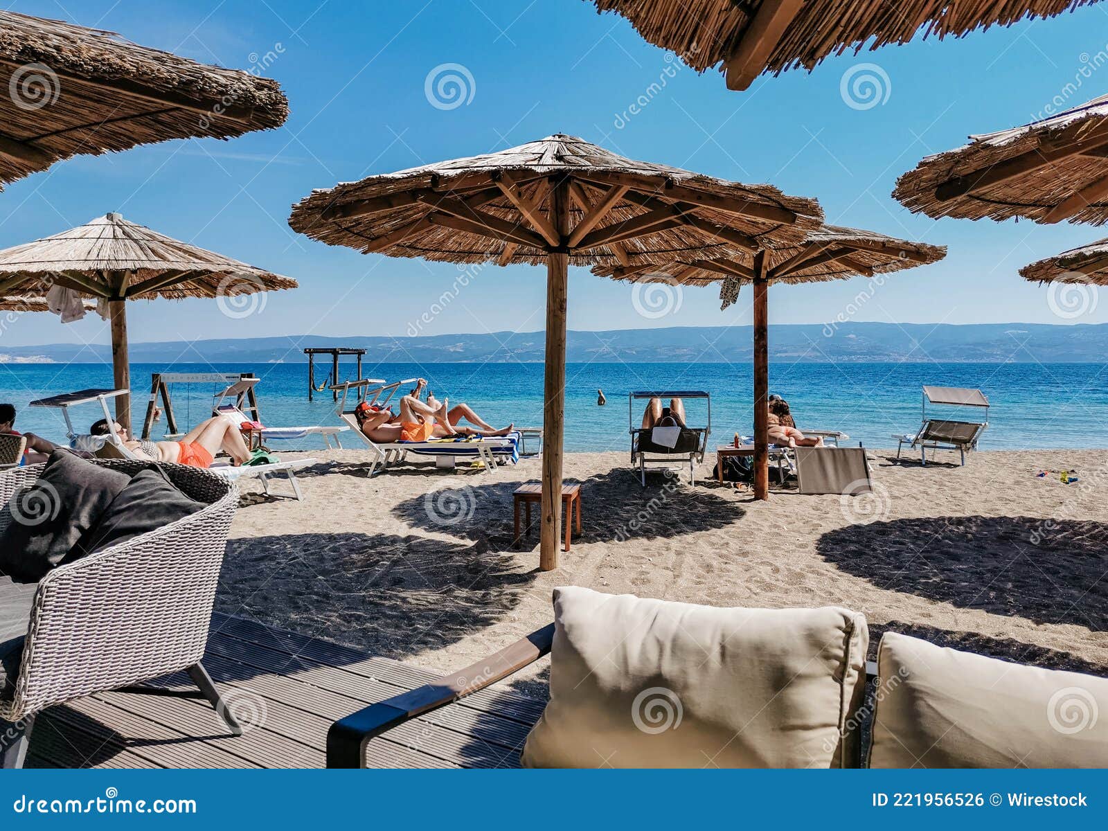 Gente Tomando El Sol Bajo Las Sombrillas En La Playa De Arena Durante