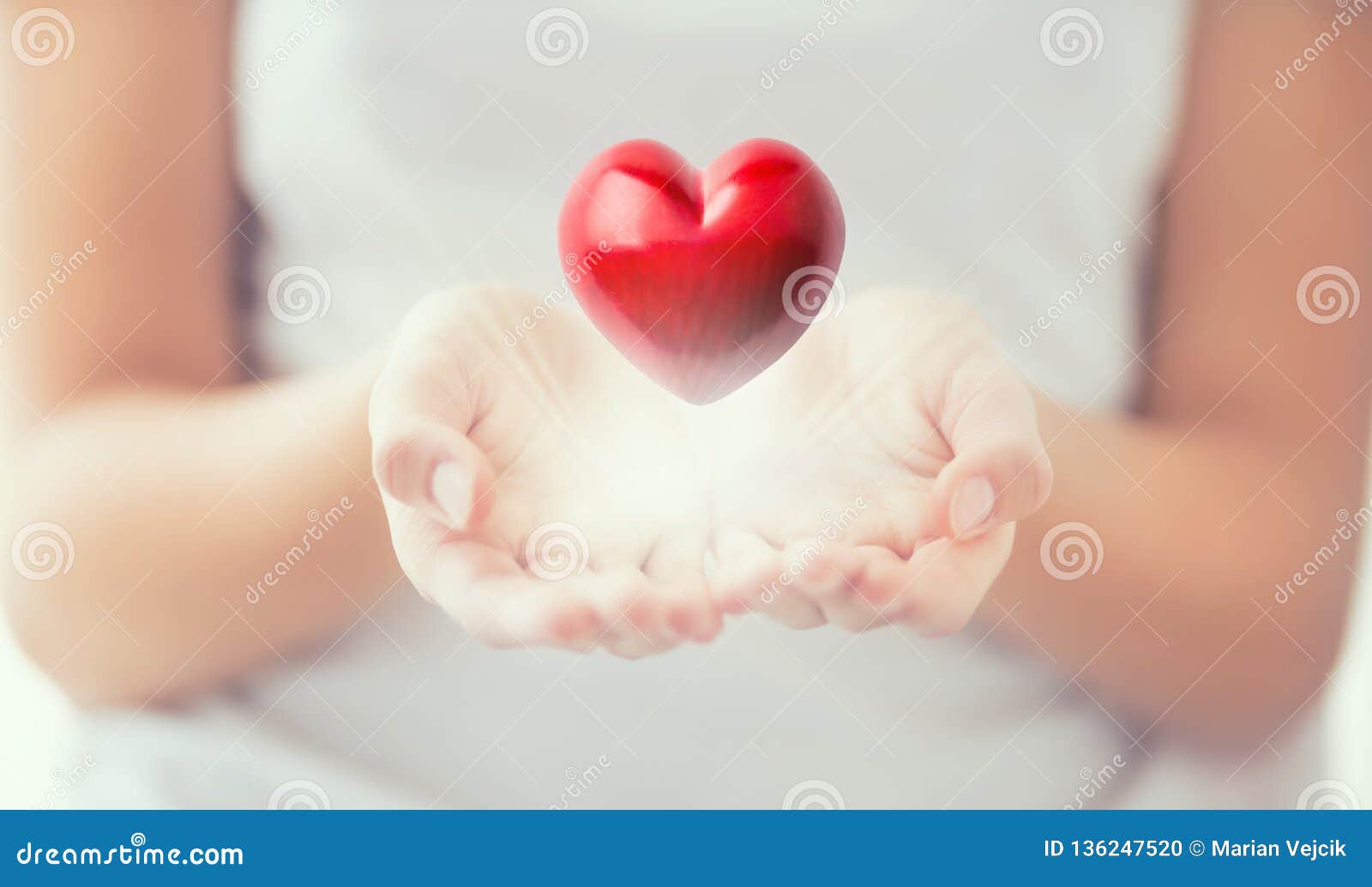 gentle womens hands and a red heart glowing in his hands. valentines mothers day and charity concept