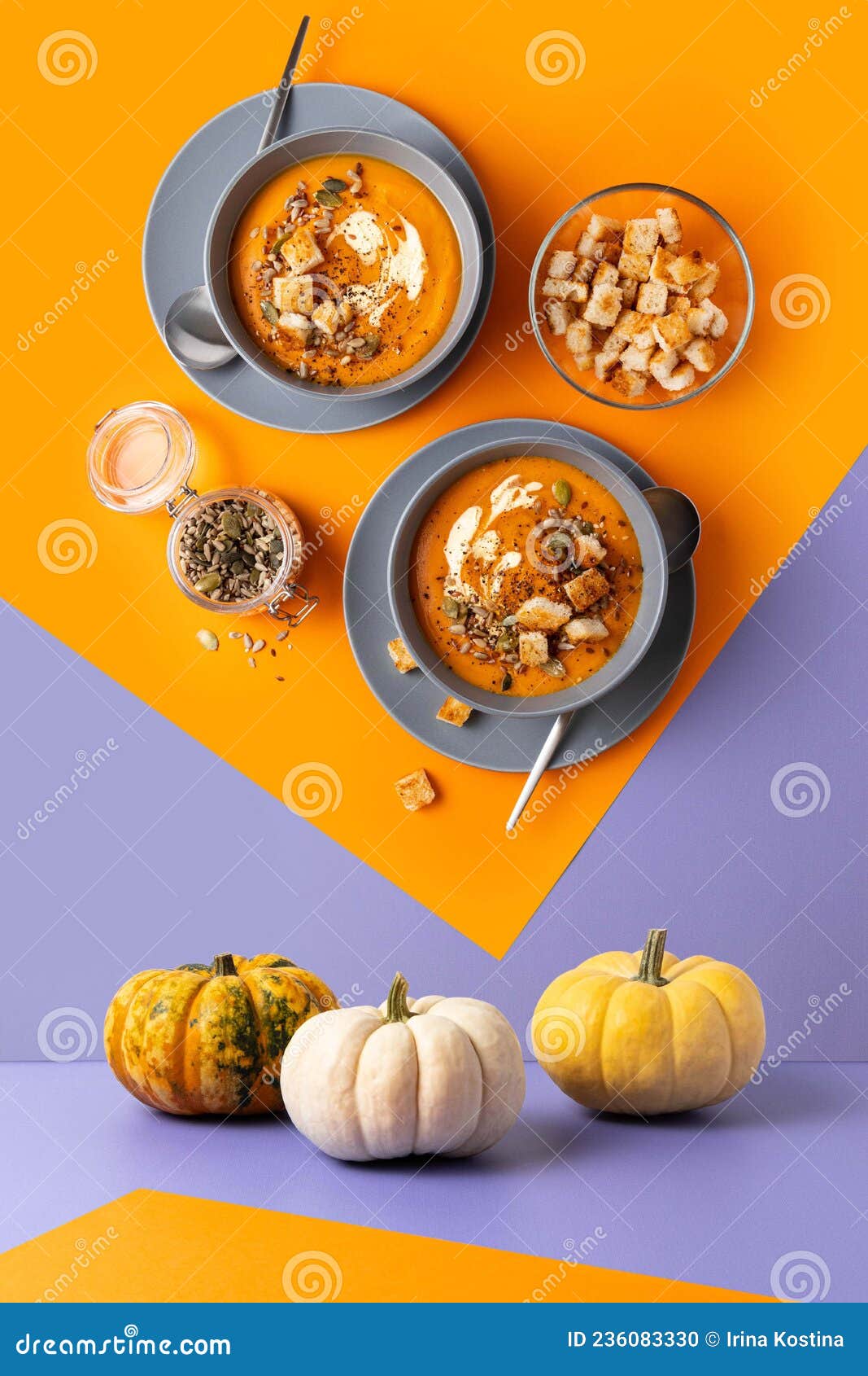 geometric composition with pumpkin soup with cream, seeds and toasts on orange and violet backgroumd.