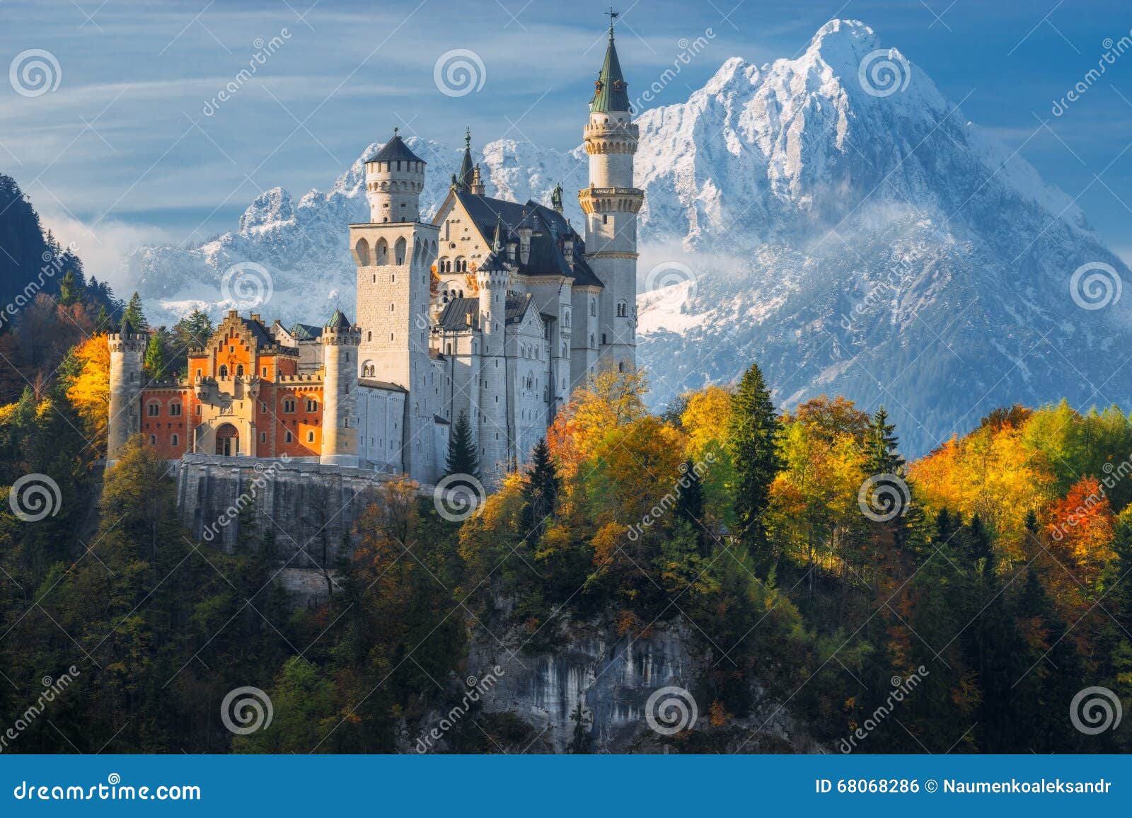 germany. famous neuschwanstein castle in the background of snowy mountains and trees with yellow and green leaves.