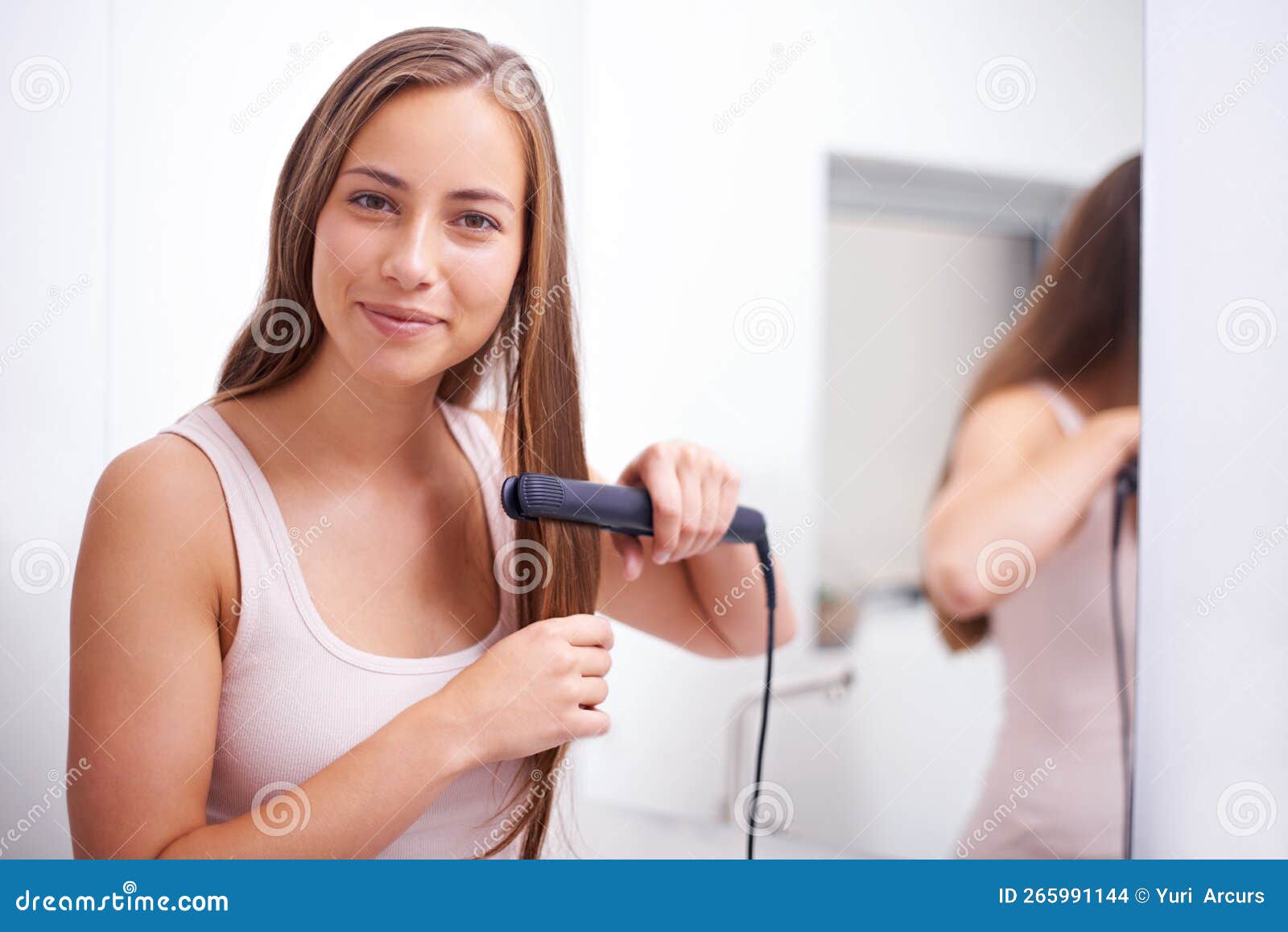 Getting that Sleek Look. a Woman Using a Flat Iron on Her Hair. Stock