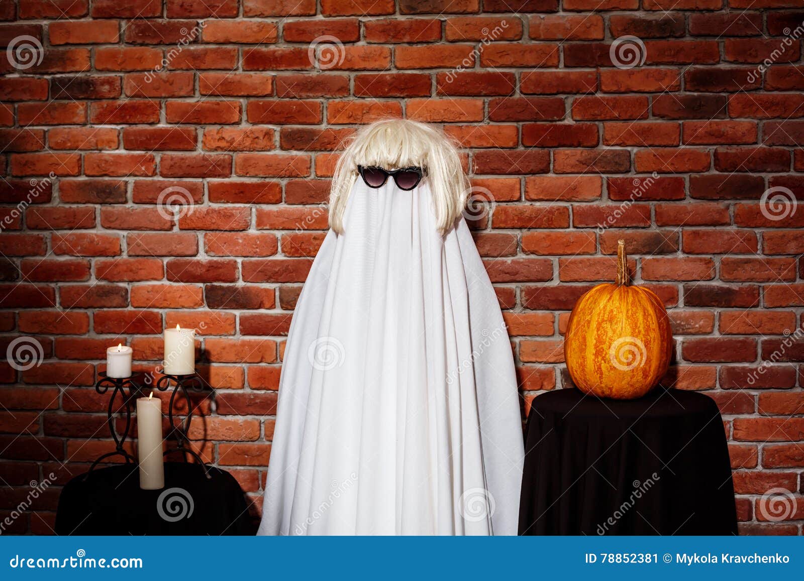 Ghost in Sunglasses and Wig Posing Over Brick Background. Halloween