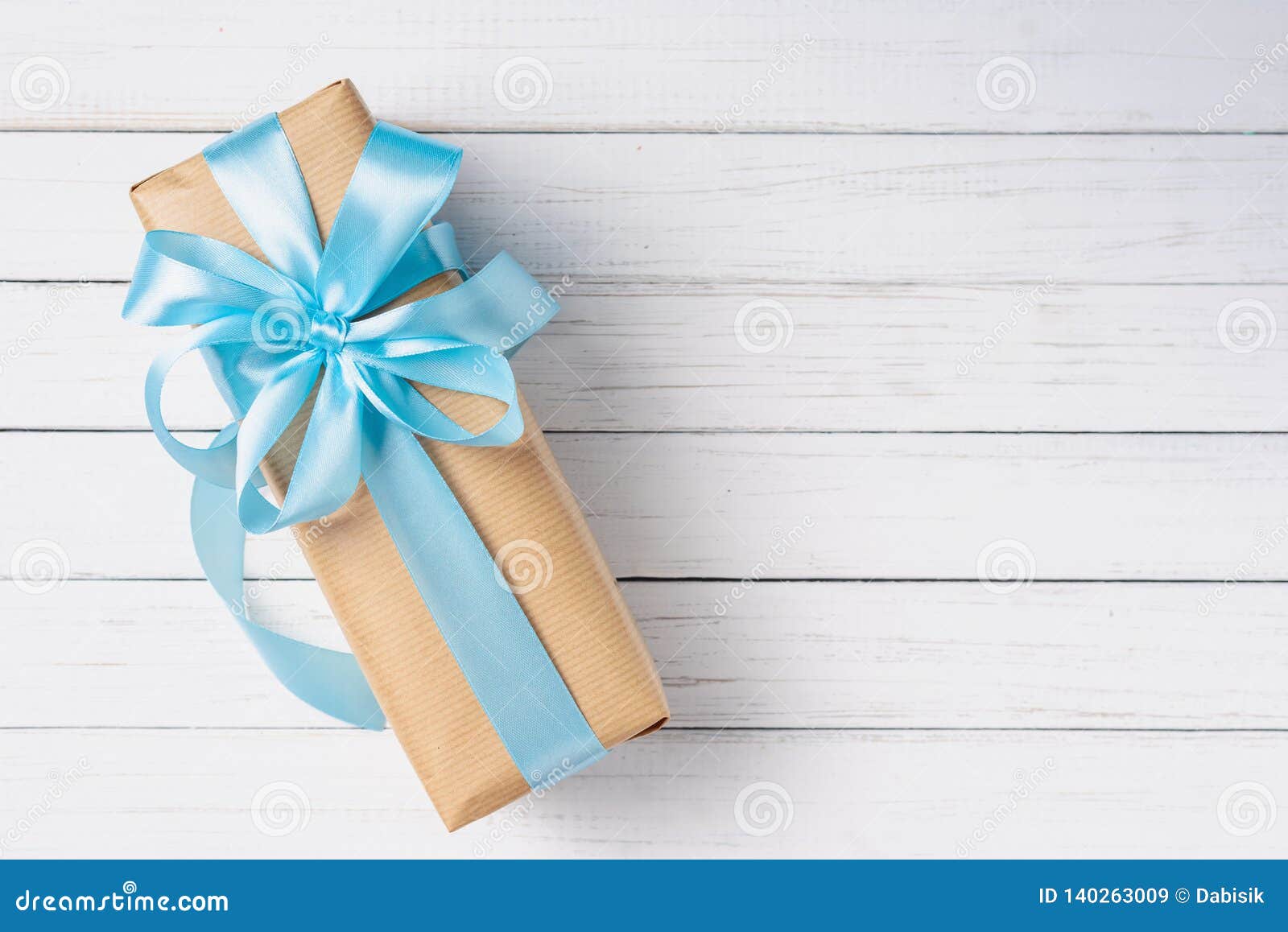 Gift Box with Blue Bow on a White Wooden Background with Copy Space