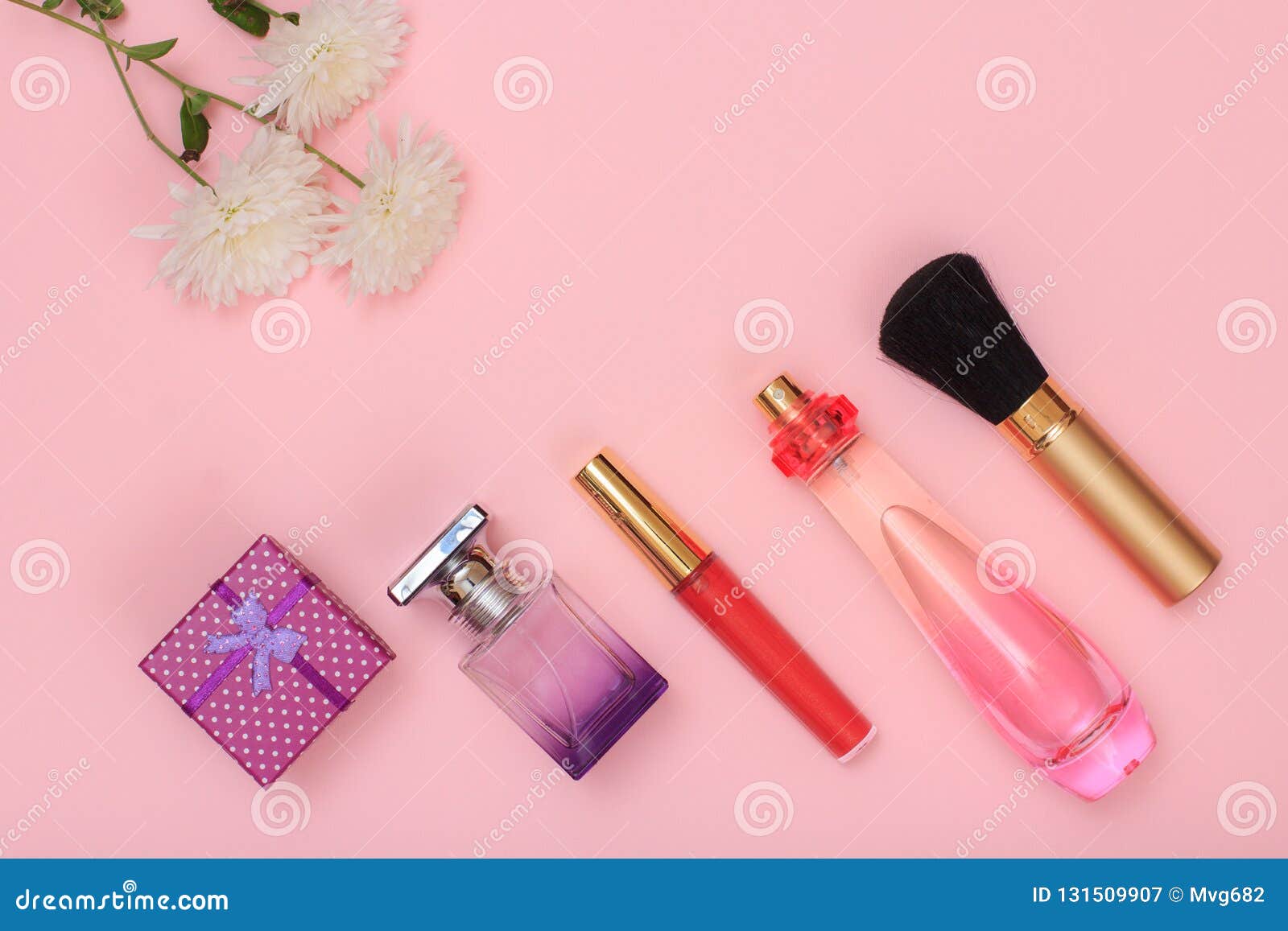 Gift Box, Bottles of Perfume, Brush and Flowers on a Pink Background