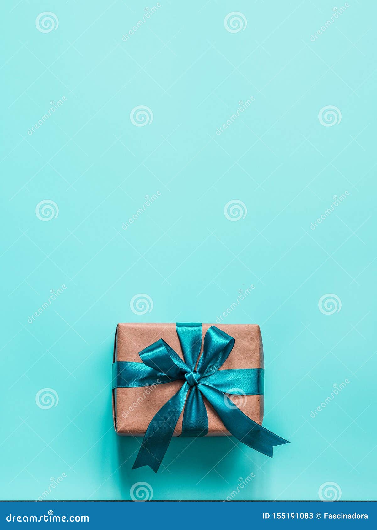 Gift box in craft wrapping paper and green satin ribbon on white