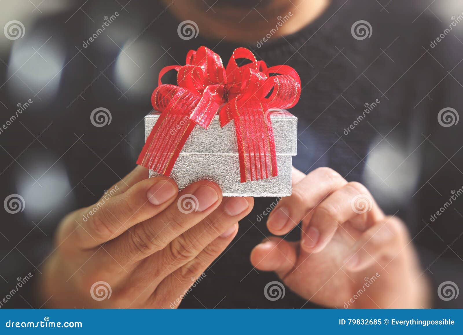 gift giving,man hand holding a gift box in a gesture of giving.blurred background,bokeh effect