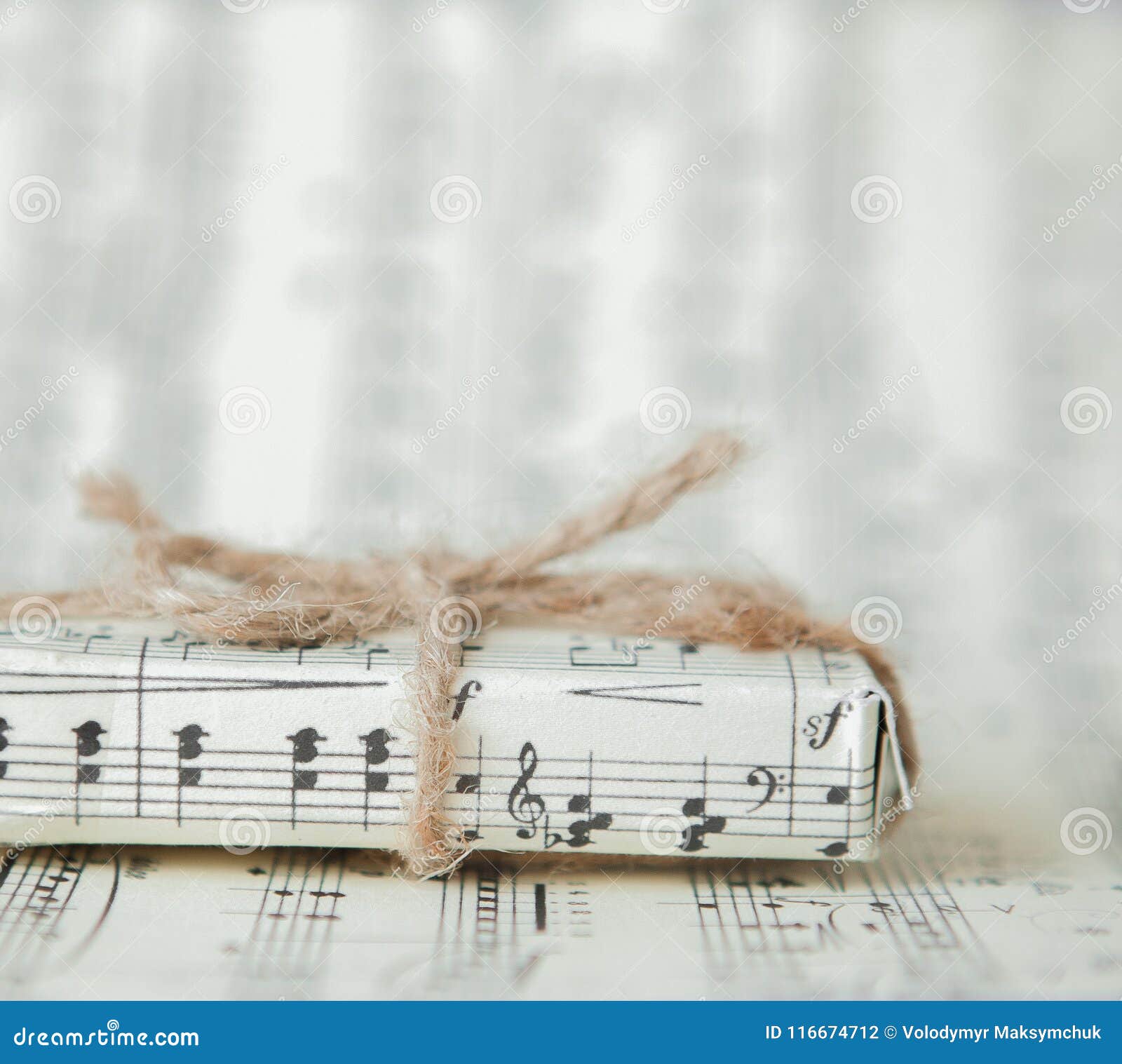 Giftbox On Music Sheet. A Musical Gift On Notes Background Stock Photo