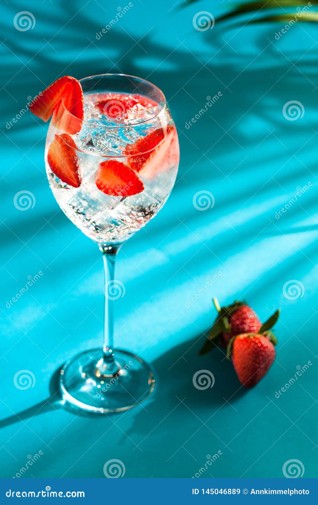 gin fizz cocktail with strawberries on turquoise background