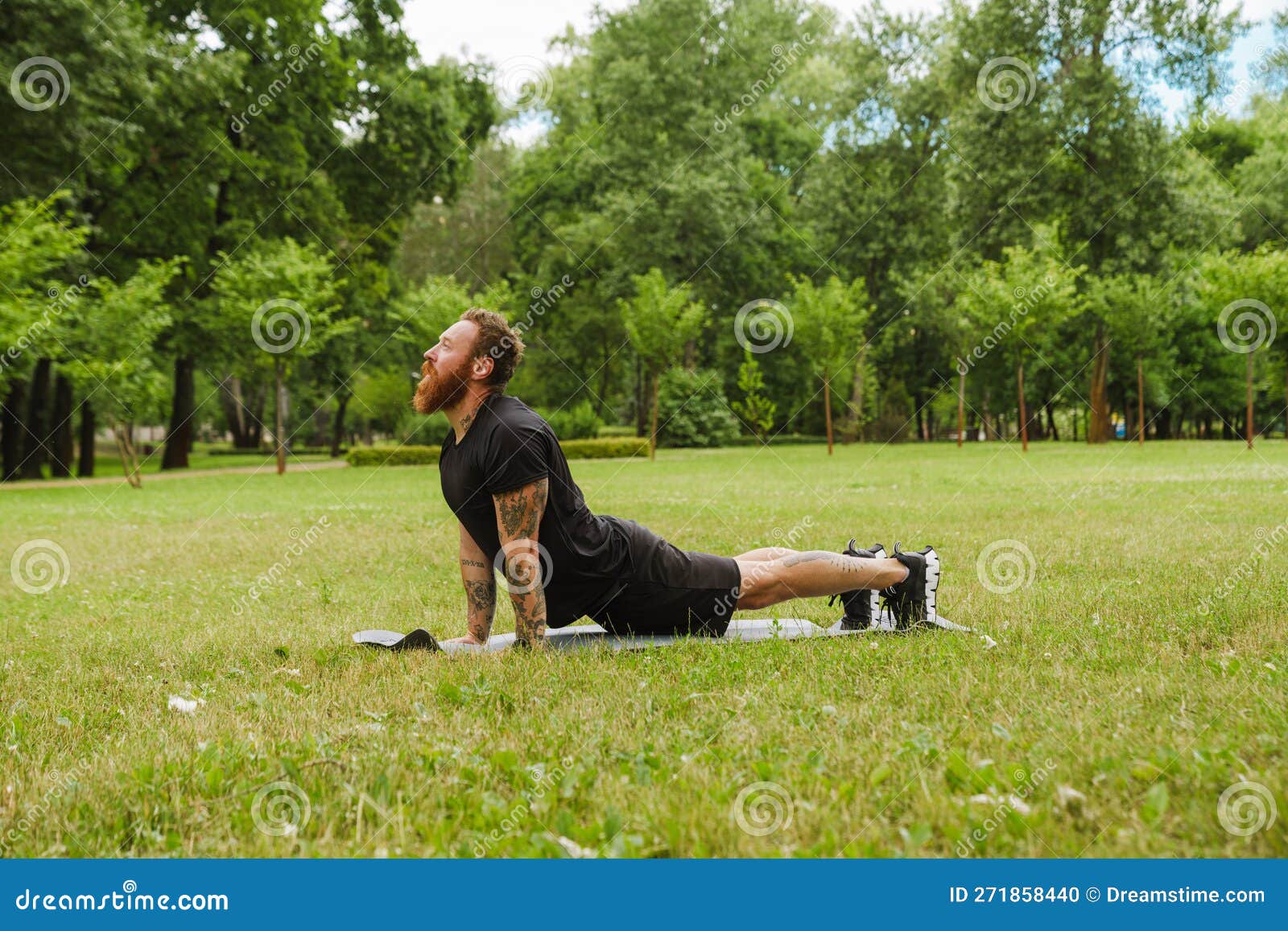 Ginger Bearded Man Doing Exercise during Yoga Practice in Park Stock