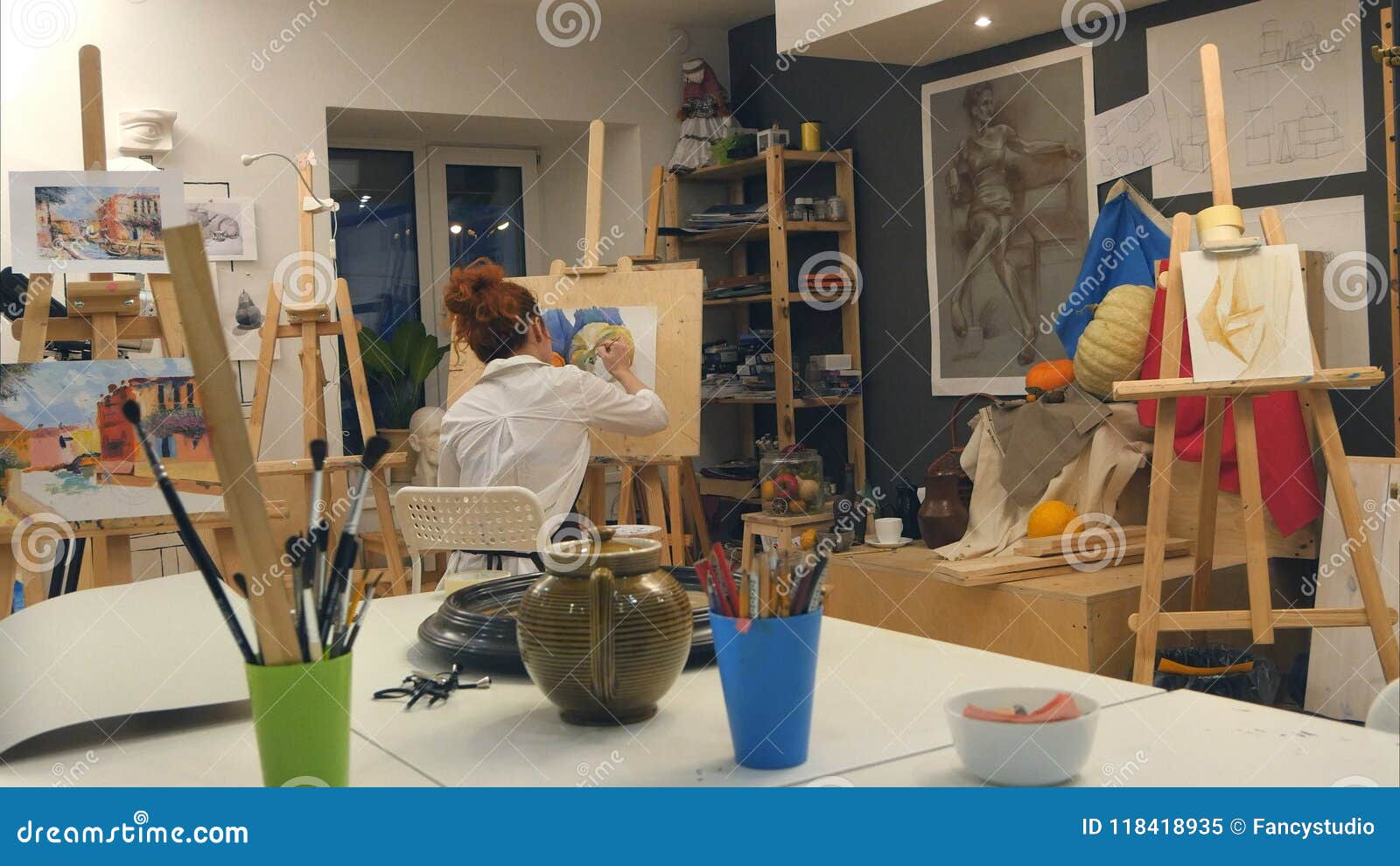 ginger female artist painting still life in art studio