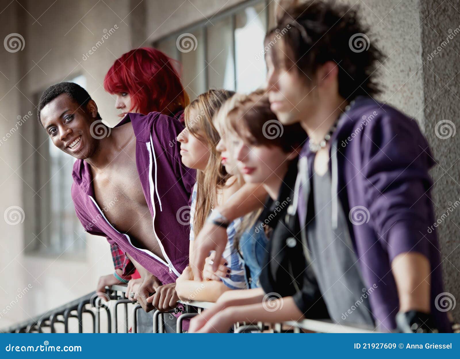 Giovane afroamericano teenager ed amici. Un gruppo di giovani anni dell'adolescenza della roccia punk fissa nella distanza come sorrisi teenager dell'afroamericano attraente verso la macchina fotografica.