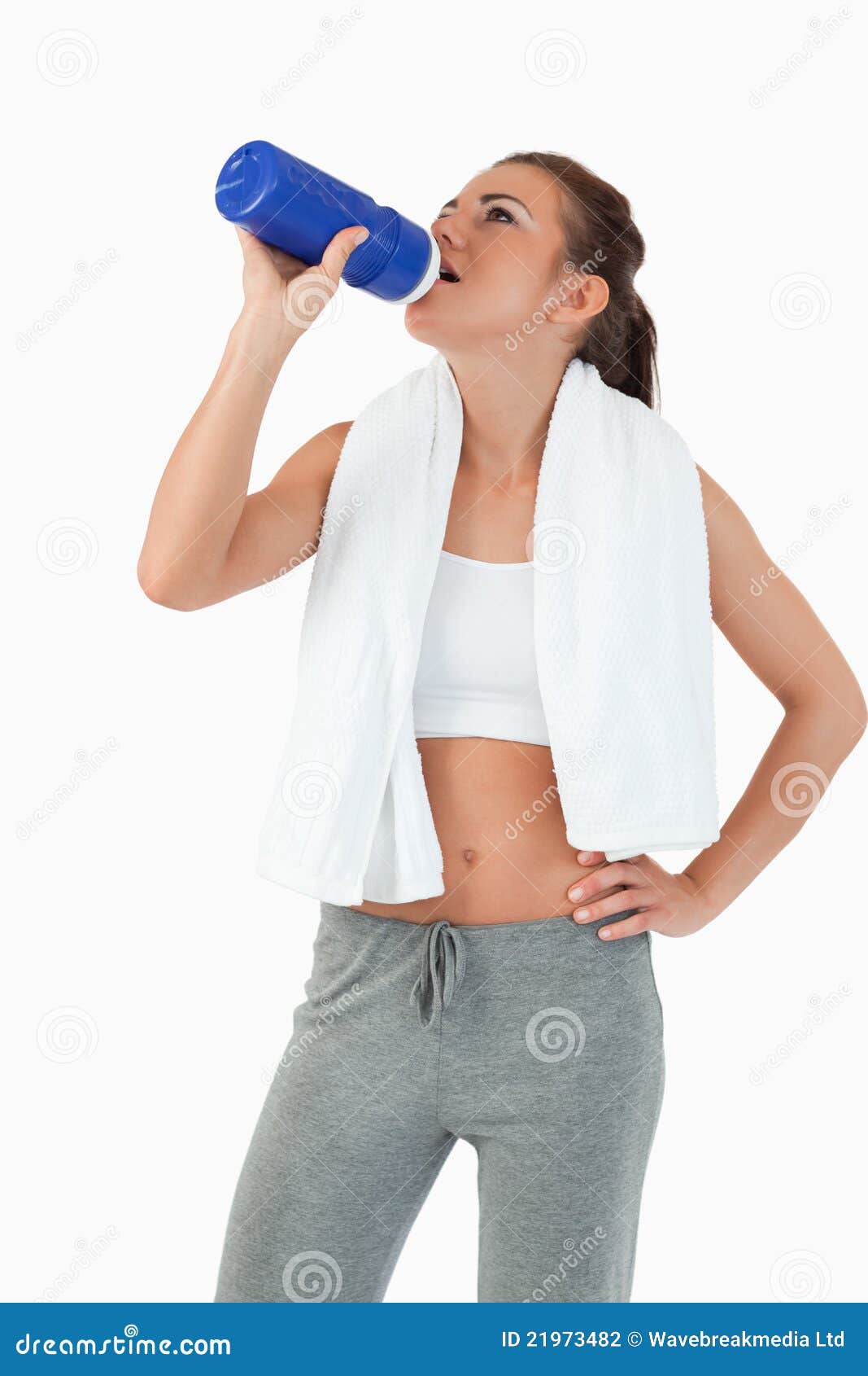 Giovane femmina che cattura un sip dalla sua bottiglia dopo l'allenamento contro una priorità bassa bianca