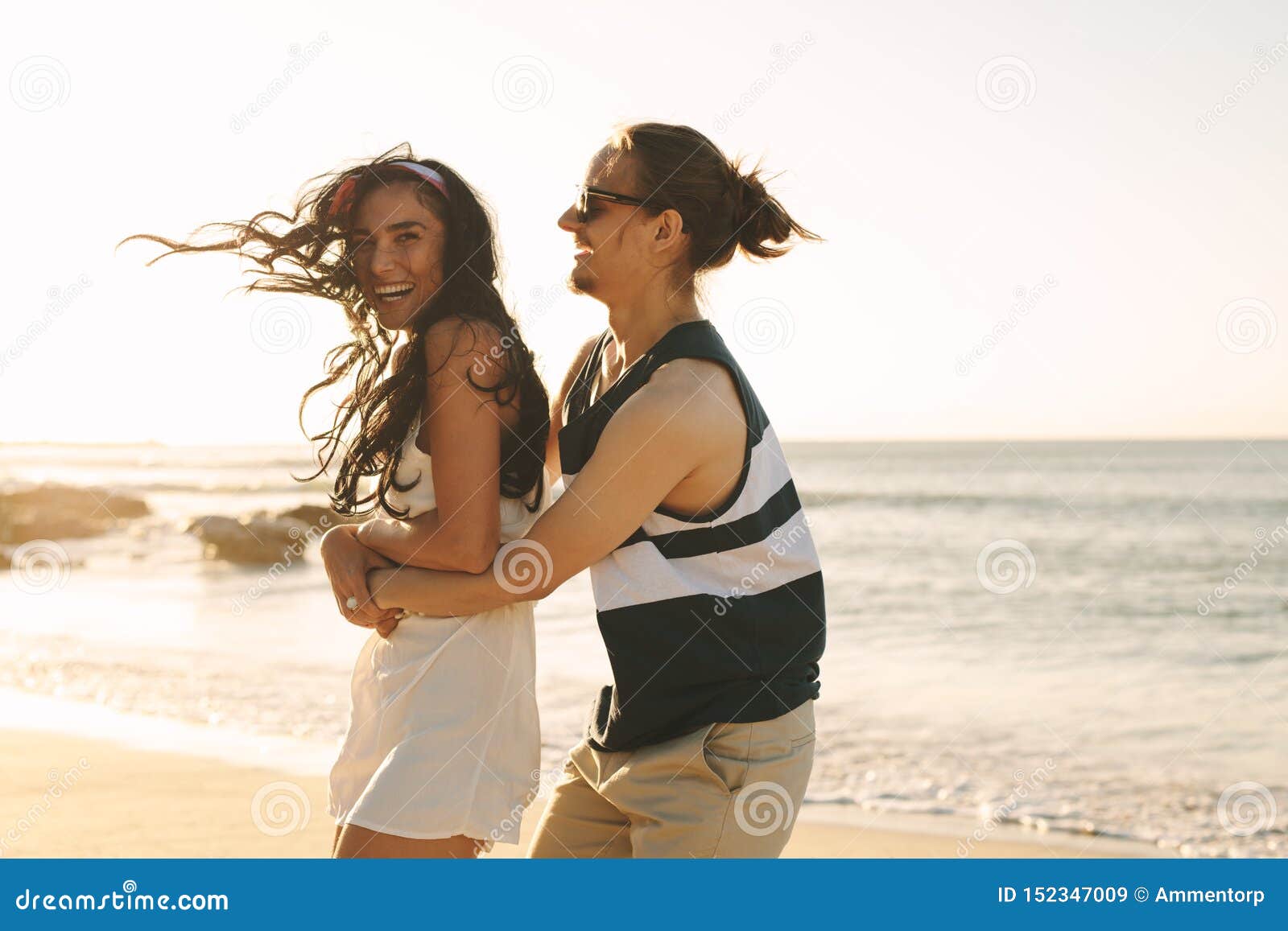 Giovani coppie allegre sulla vacanza della spiaggia. Giovani coppie felici divertendosi insieme sulle vacanze estive alla spiaggia Giovani che tengono la sua amica da dietro e sorridere