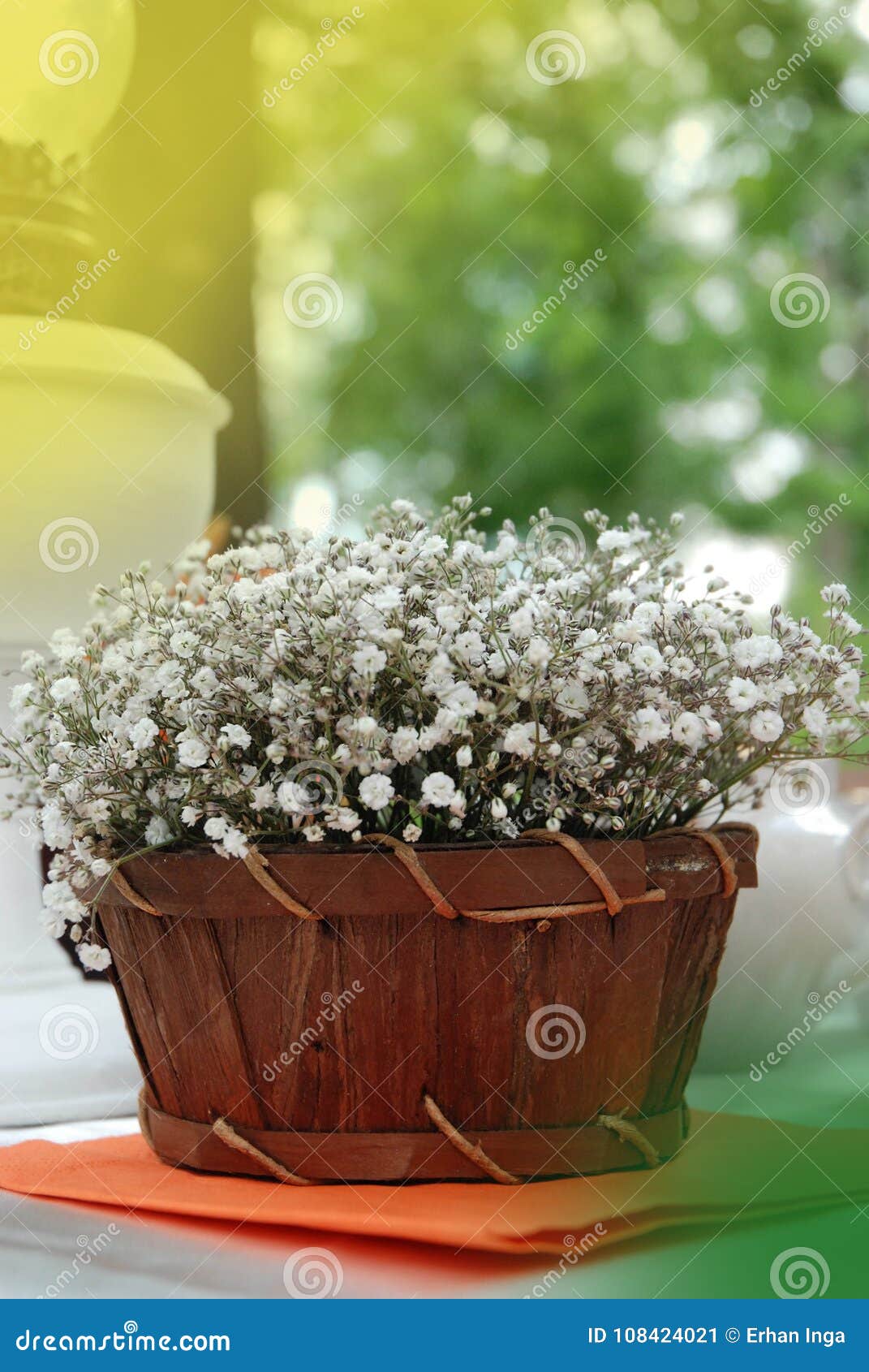 Gipsofila ordning i korg eller träask, på tabellen med Blured trädgårdbakgrund Vår- och sommarblommor tonat vertikalt