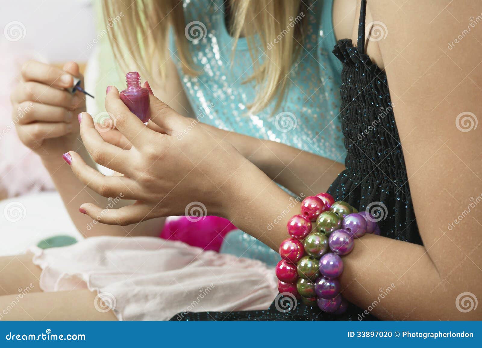 girl applying nail polish to friend's fingernails