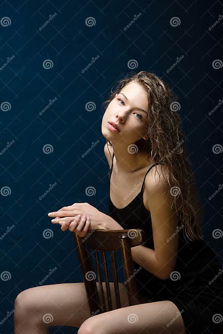 A Girl With Beautiful Bright Skin Sits On A Wooden Chair Wet Curly Hair Lies On Her Shoulders