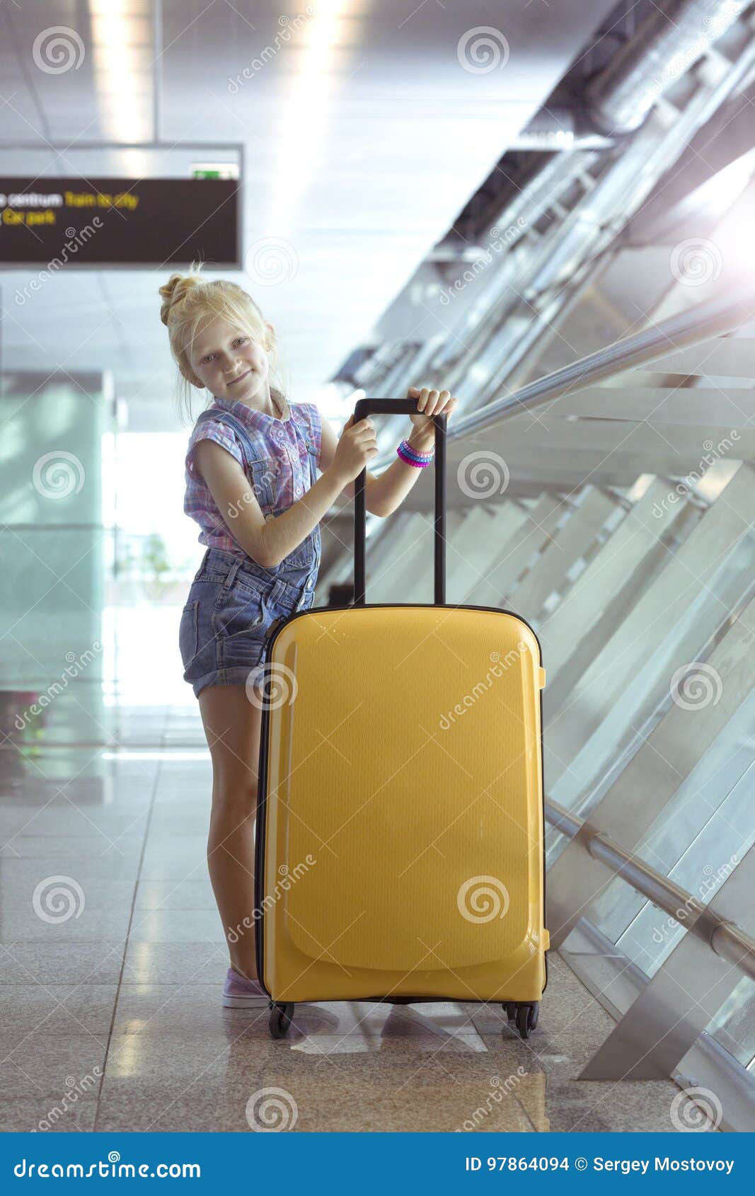 Girl and beautiful yellow suitcase stands in the airport corridor