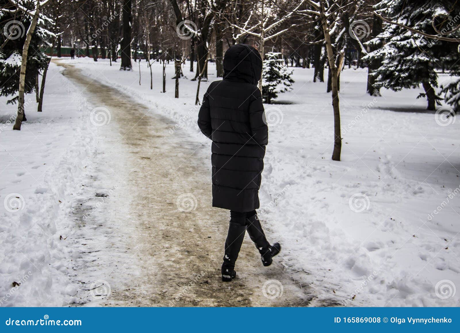 A Girl in a Black Coat is Walking Along the Road. Silhouette of a Girl ...