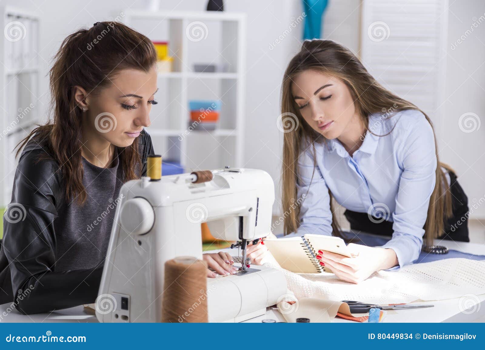 Girl in Black is Sewing. Her Colleague is Looking at Notes Stock Photo ...