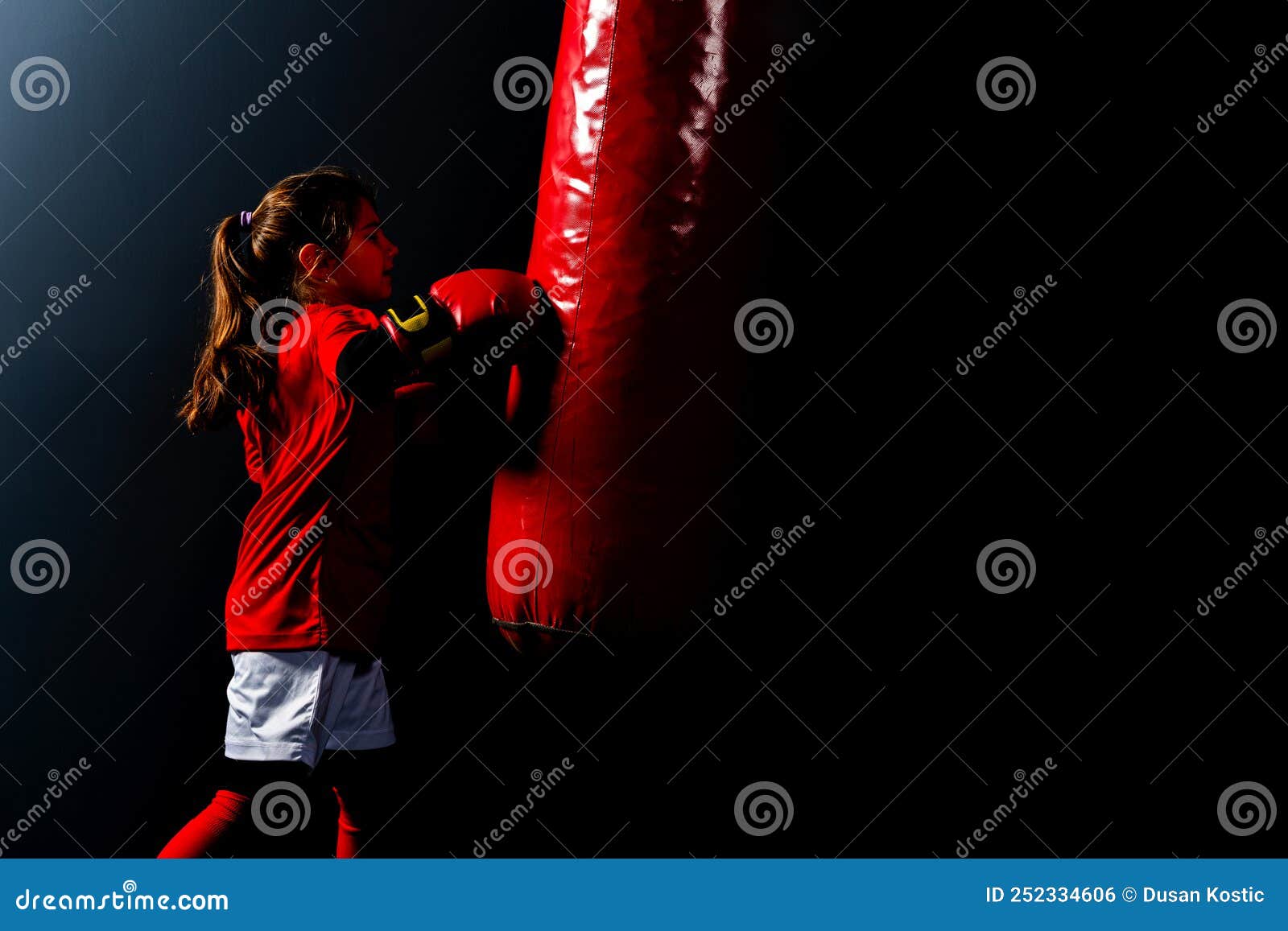 a girl in boxing gloves hits a punching bag