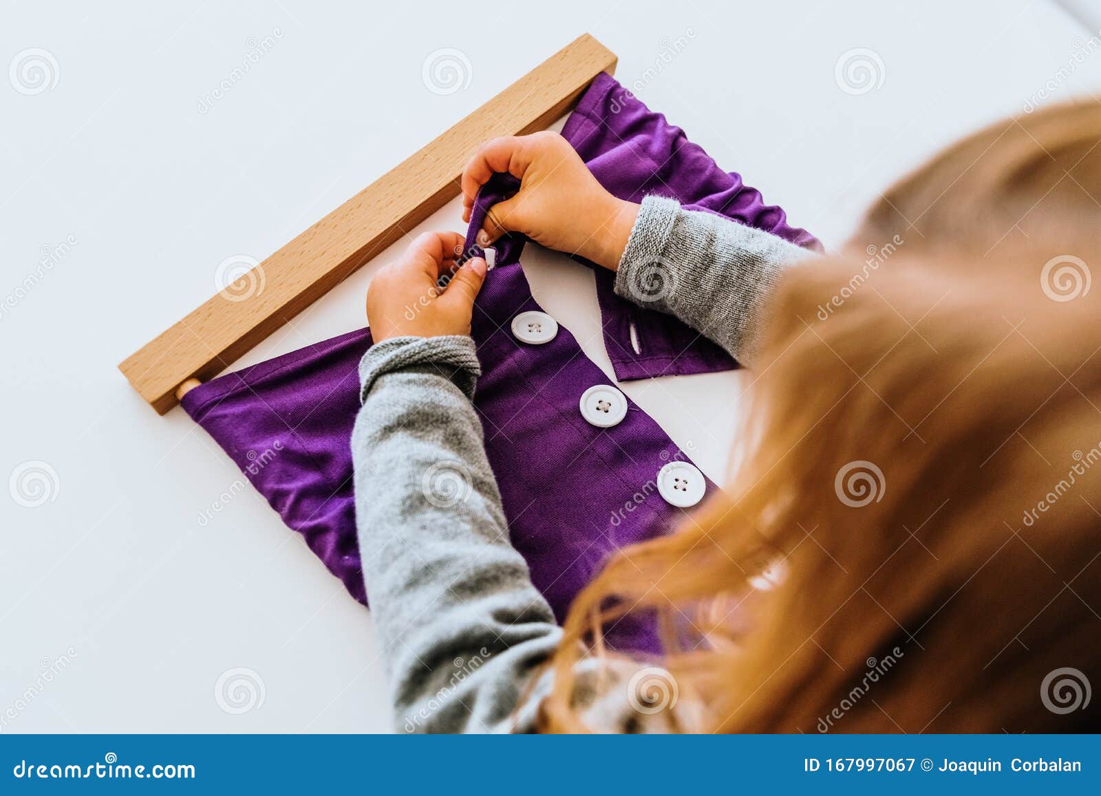 girl buttoning a montessori frame to develop the dexterity of her fingers