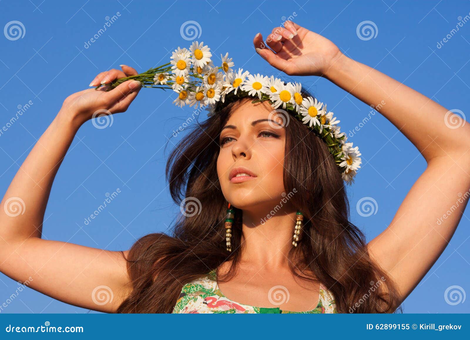 Girl on camomile field. Girl in camomile wreath with blue sky at background