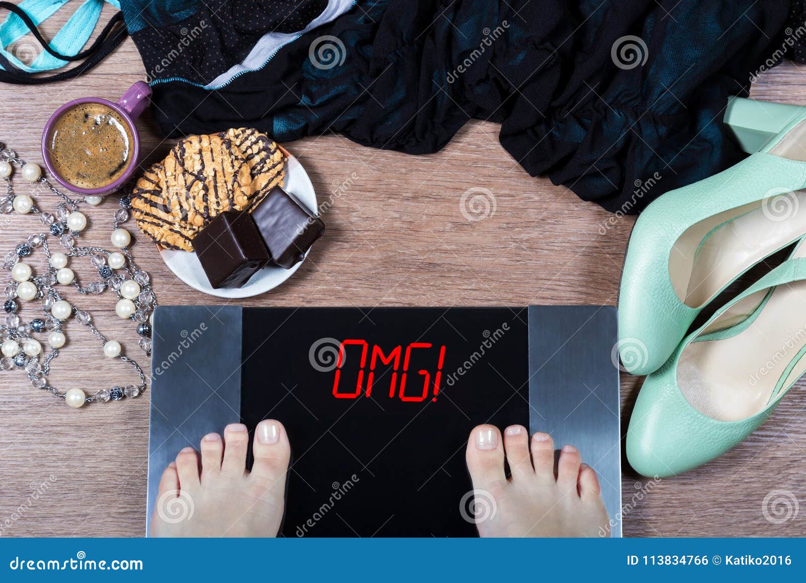 girl checks her weight on digital scales. sign omg! on balance surrounded by cup of coffee, sweets and female clothes and shoes