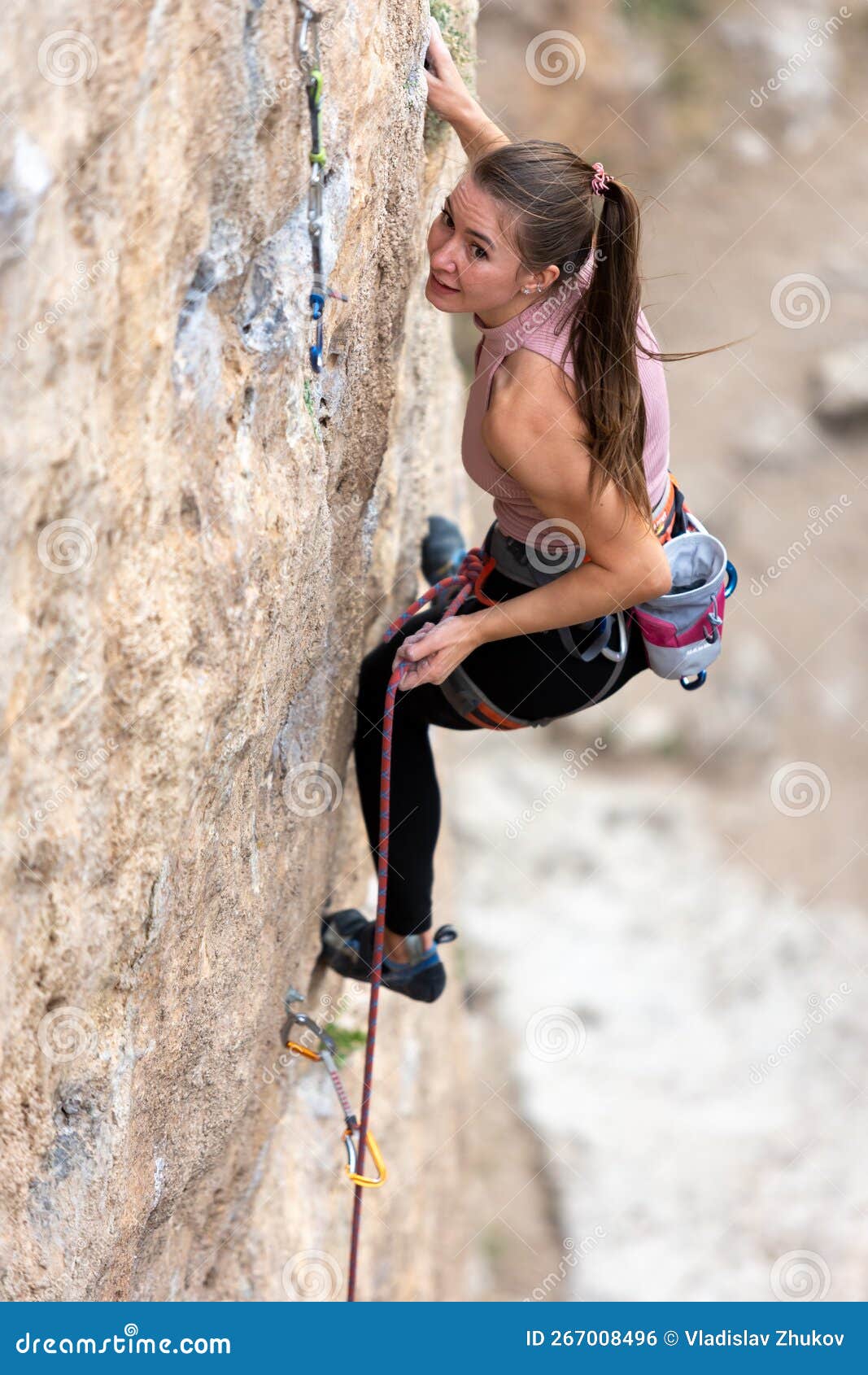 Girl Climber Snaps a Rope into a Quickdraw. Rock Climber on a Difficult