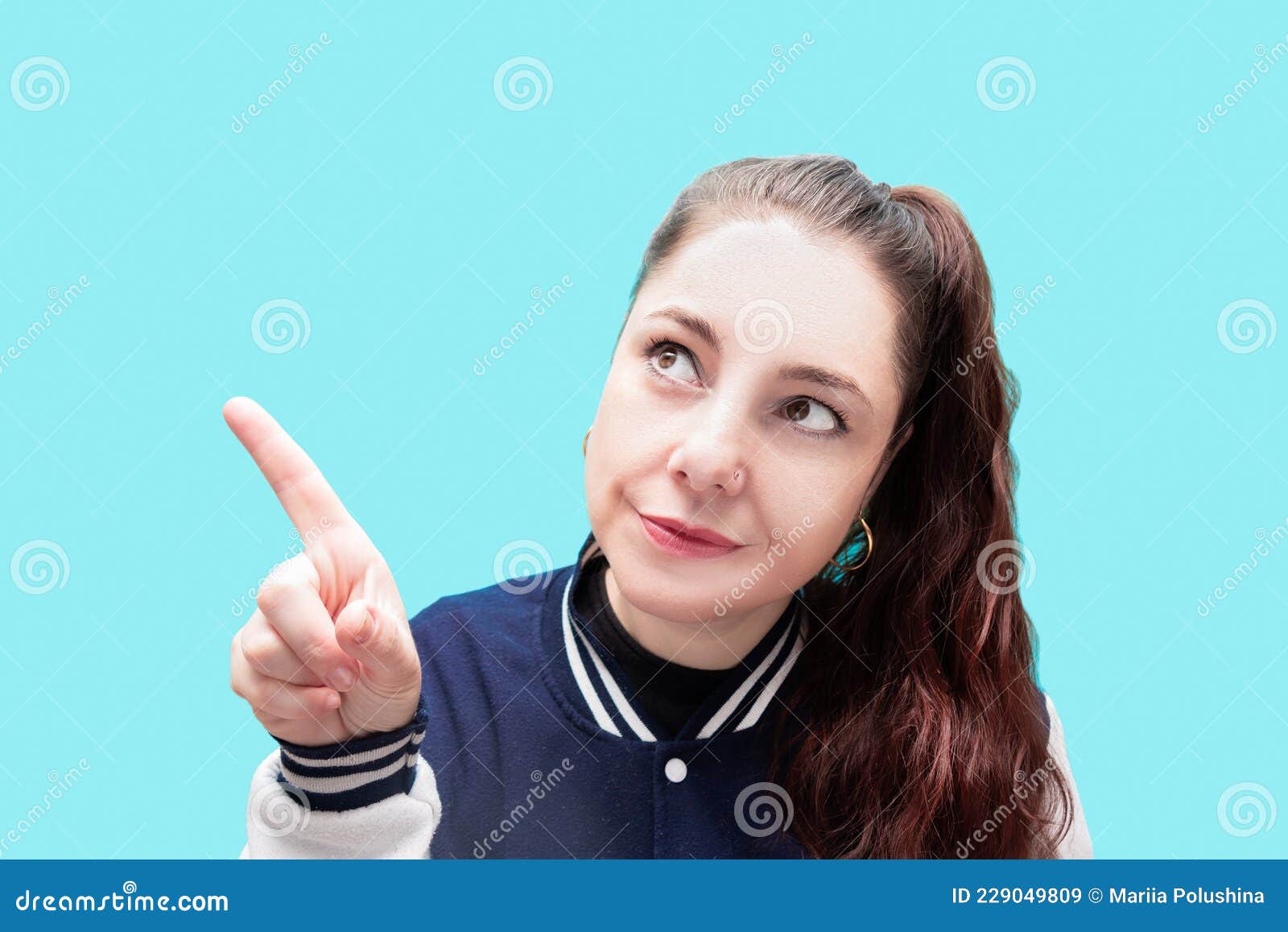Girl In College Jacket With Ponytail Pointing With Index Finger To The ...