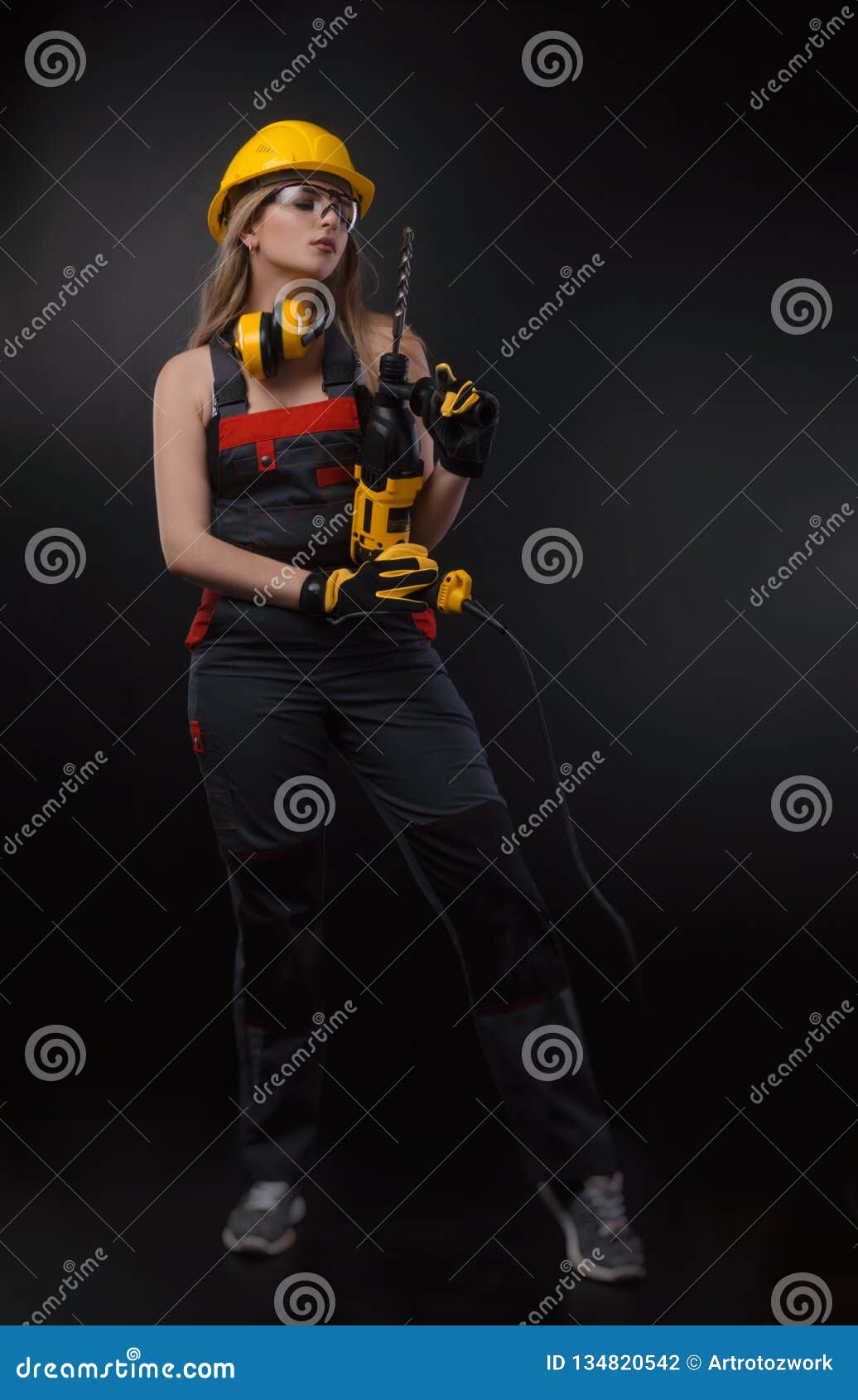 Girl in Construction Clothes and Protective Equipment Posing with a