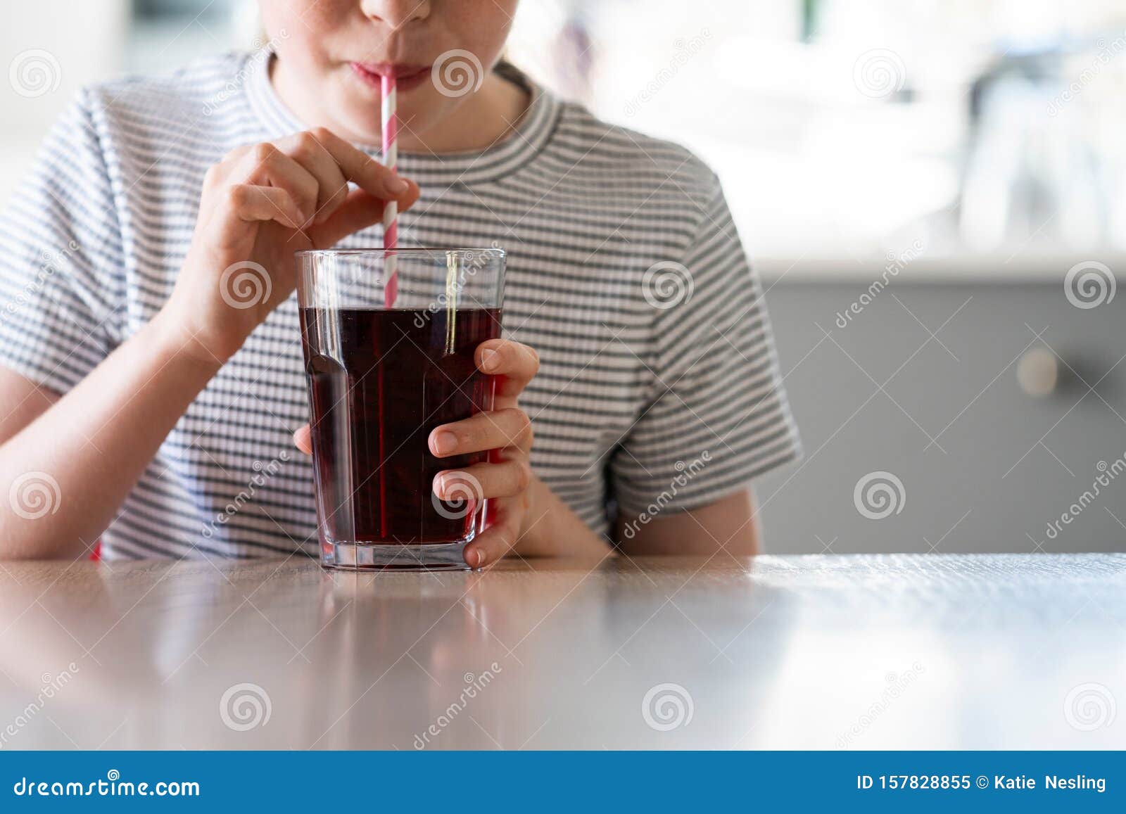 close up of girl drinking sugary fizzy soda from glass with straw