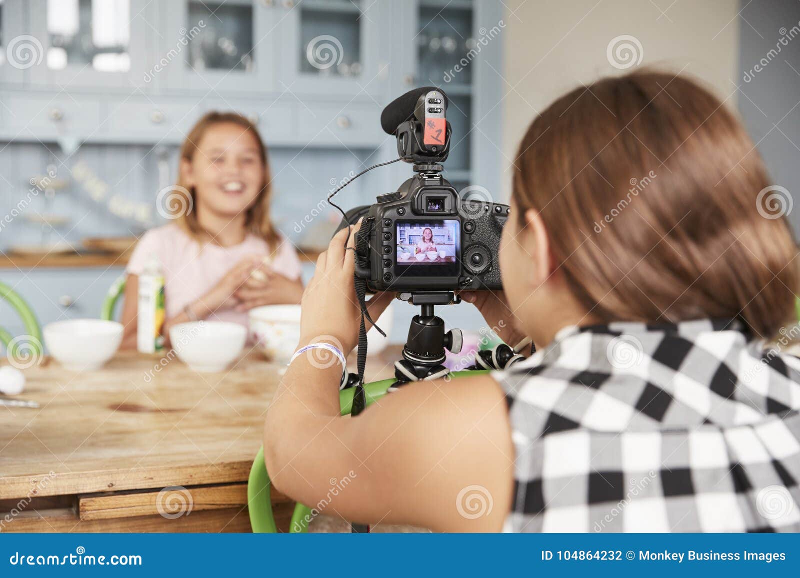 girl filming her friend for cookery video blog in kitchen