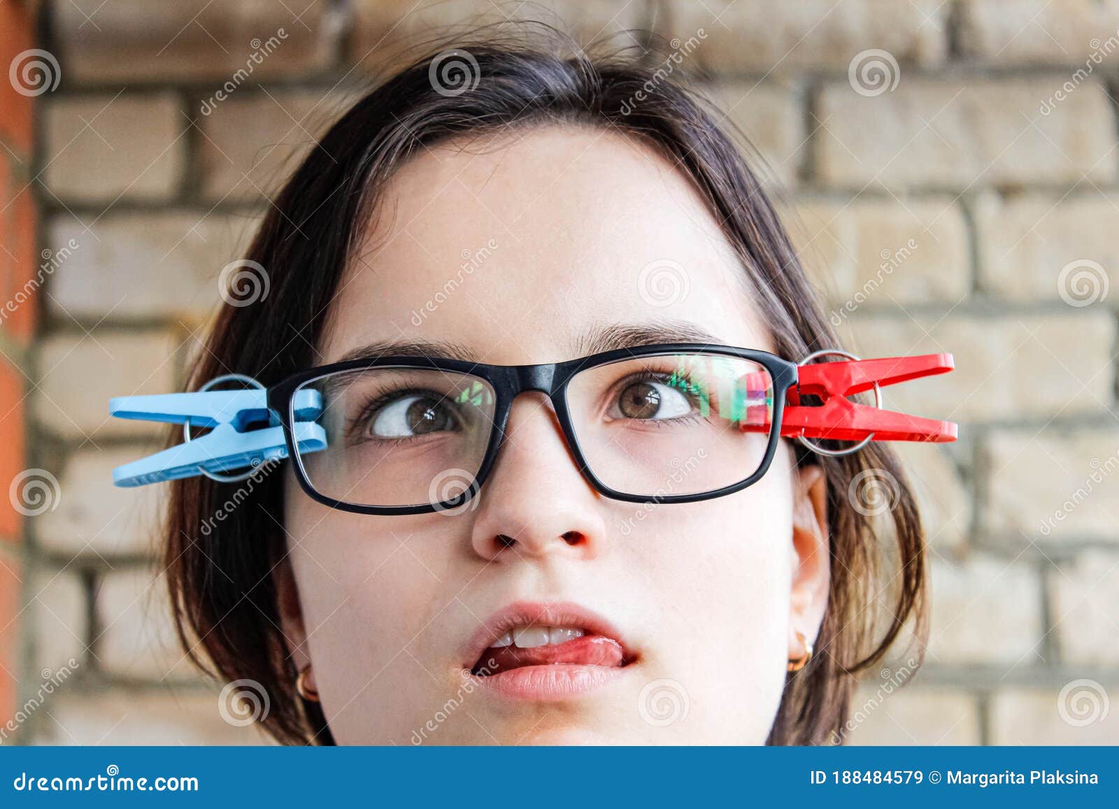 A Girl With Glasses With Slanted Eyes And Clothespins Attached To Her 